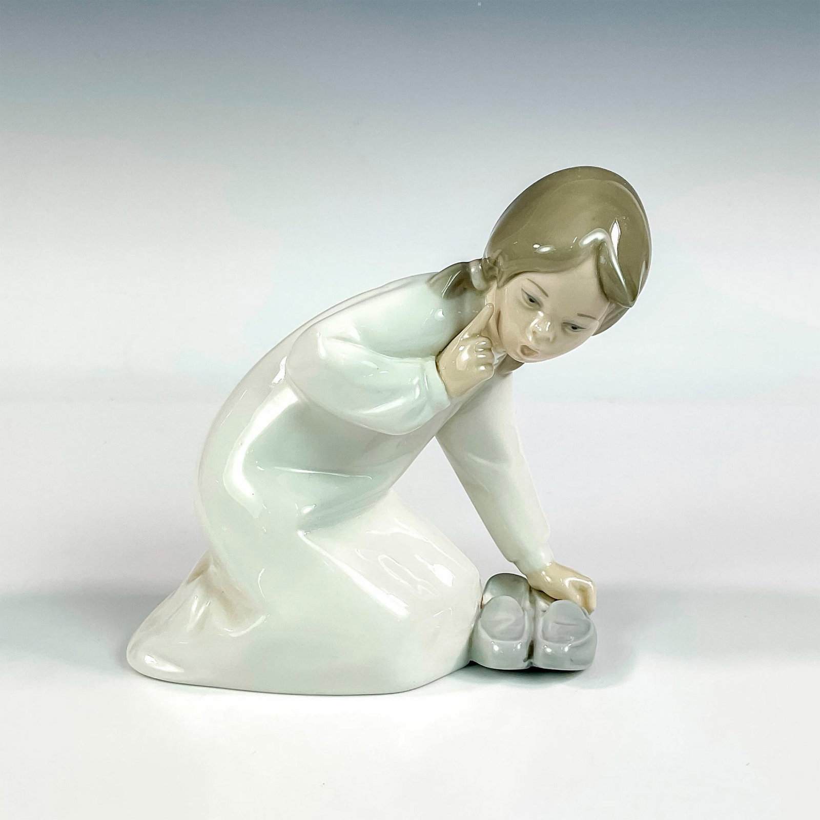 Little Girl With Slippers 1004523 - Lladro Porcelain Figurine: Glossy finish; Lladro backstamp. Artist: Vicente Martinez Issued: 1969 - 1993 Dimensions: 5.5"H Manufacturer: Lladro Country of Origin: Spain
