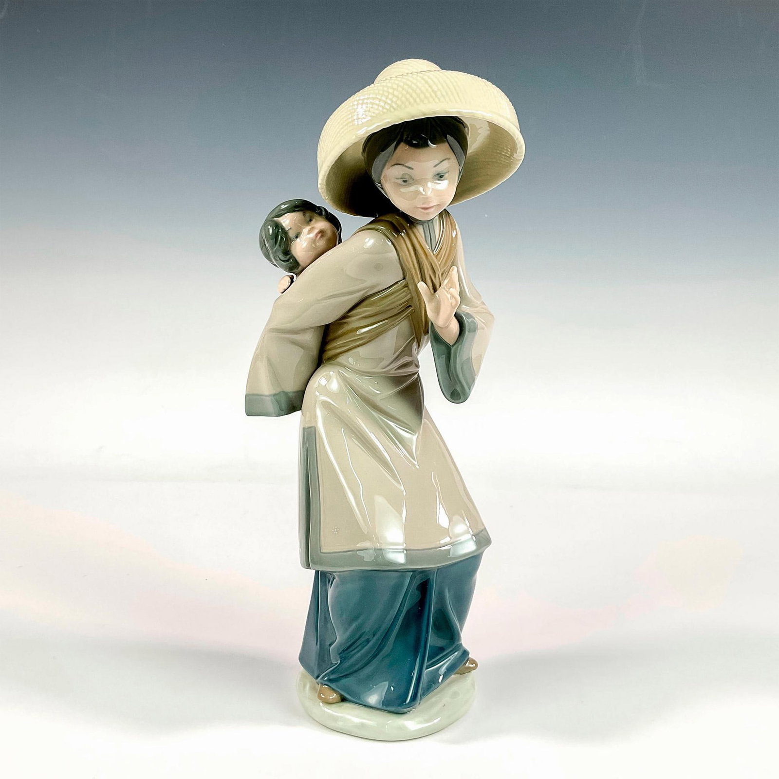 My Precious Bundle 1005123 - Lladro Porcelain Figurine: Glossy finish; Lladro backstamp. Artist: Salvador Debon Issued: 1982 - 1998 Dimensions: 10.25"H x 4.25"W Manufacturer: Lladro Country of Origin: Spain