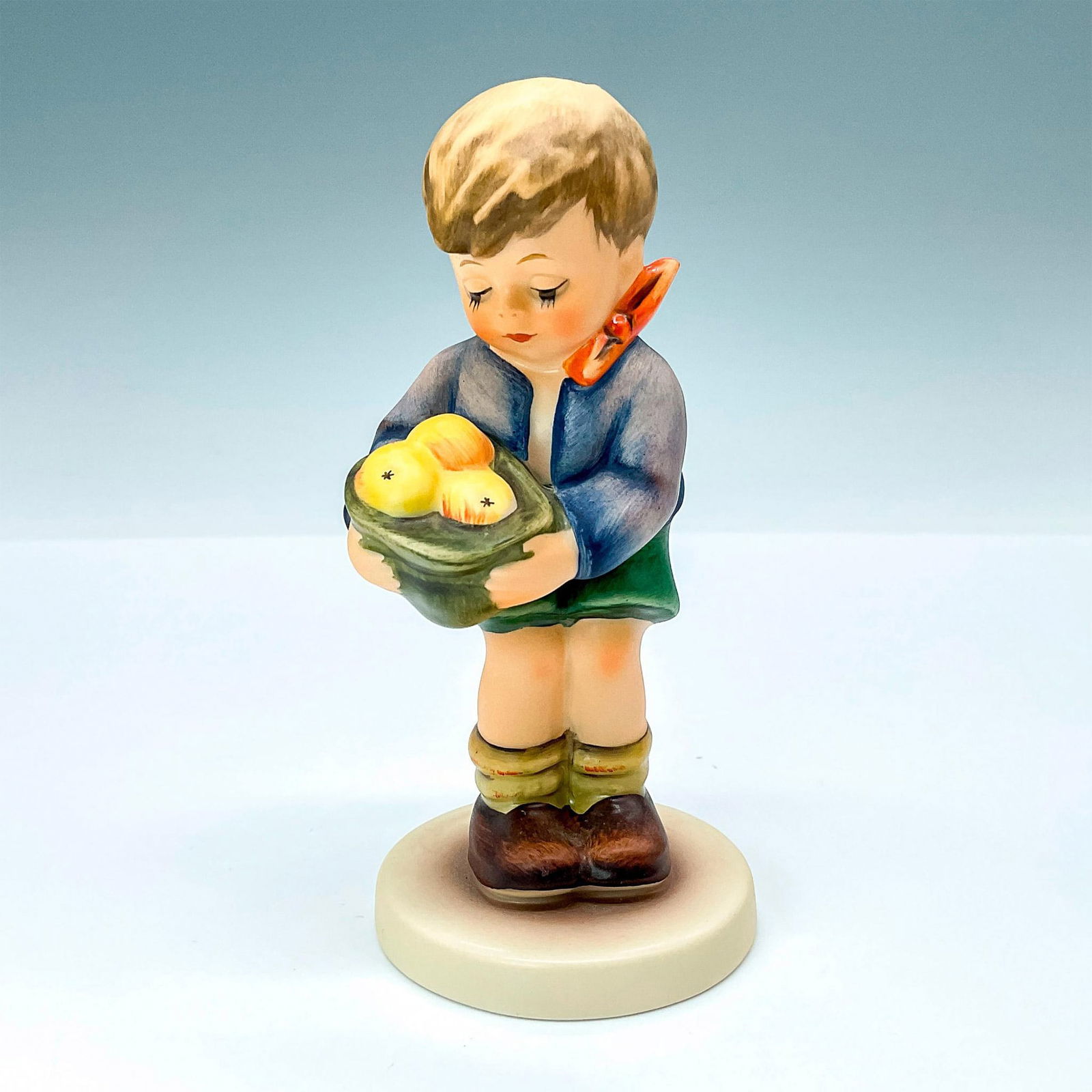 Goebel Hummel Figurine MI Hummel Club: Gift From a Friend #4852 Matte porcelain, hand painted. Young boy with crooked bowtie carrying a basket of apples. M. I. Hummel inscribed on base. 1991/1992 exclusive edition for Hummel Club members.