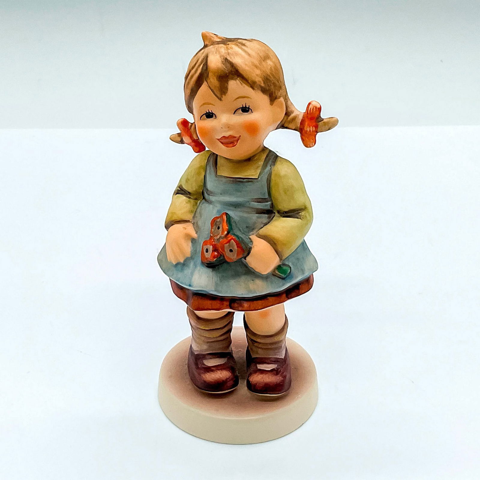 Goebel Hummel Figurine, Flower Girl HUM 548: Exclusive edition celebrating the anniversary of the 1989 figure. Hand painted figure of a young girl holding red flowers. Goebel Hummel backstamp. Issued: c. 1990s Dimensions: 2"L x 2"W x 4.5"H Manuf