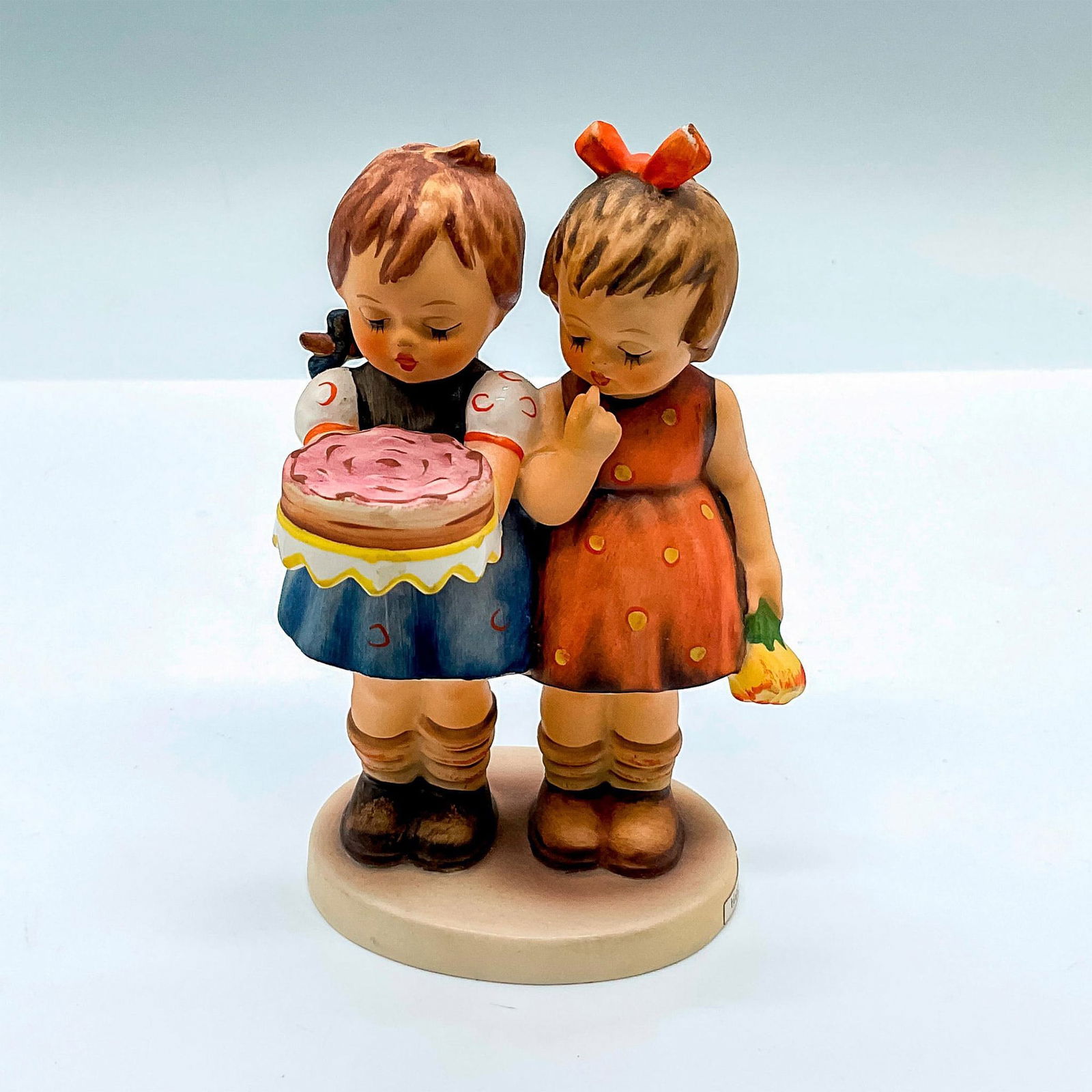 Goebel Hummel Figurine, Happy Birthday: Hand painted figure of two girls celebrating a birthday. Goebel Hummel backstamp. HUM 176/0. Issued: c. 1972-1979 Dimensions: 3.5"L x 3"W x 5.25"H Manufacturer: Goebel Hummel Country of Origin: German