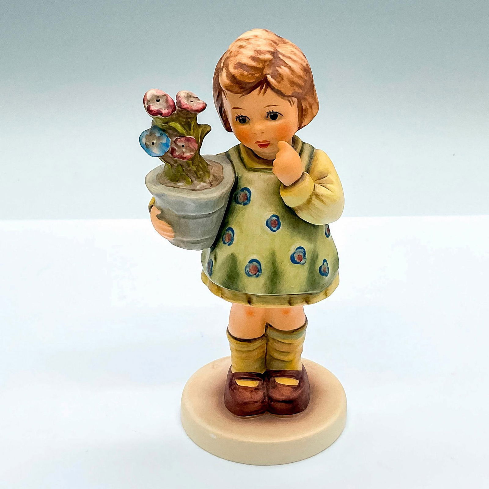 Goebel Hummel Figurine, My Wish is Small: Exclusive edition hand painted figure of a young girl with a potted flowers. Celebrating the anniversary of the 1985 molded designed by master sculptor Gerhard Skrobek. Goebel Hummel backstamp. HUM 46