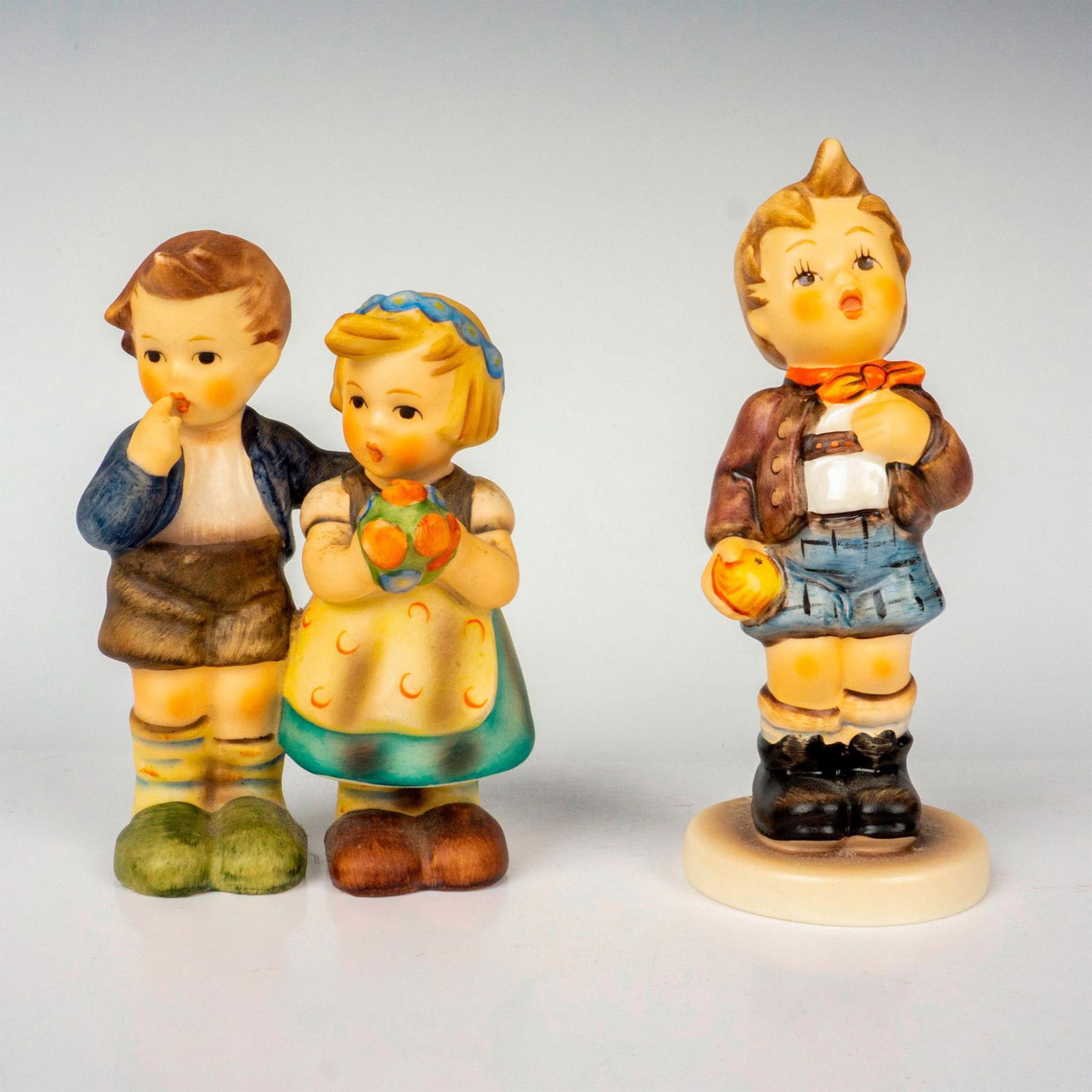 2pc Goebel Hummel Figurines, Cheeky Fellow: Hand painted in matte finish titled Cheeky Fellow and We Congratulate. M. I. Hummel impressed backstamp. Goebel backstamp. Tallest measures: 2.75"L x 1.75"W x 3.75"H. Shortest measures: 1.75"W x 4.5"H