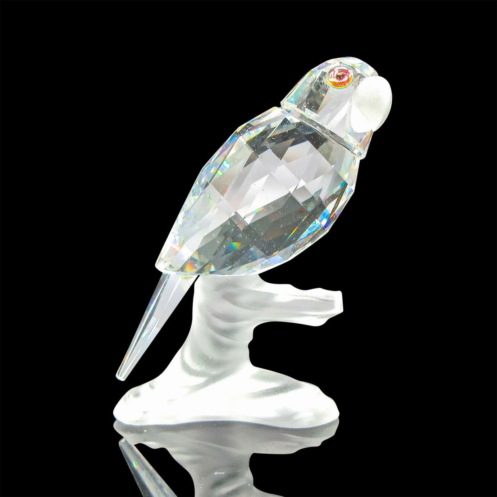 Swarovski Silver Crystal Figurine, Parrot: Part of the Up in the Trees group. Clear faceted body with iridescent eyes perched on frosted branch. Swarovski backstamp. 7621000004. This item has its original box: 3.25"L x 3.25"W x 5"H. Artist: Mi
