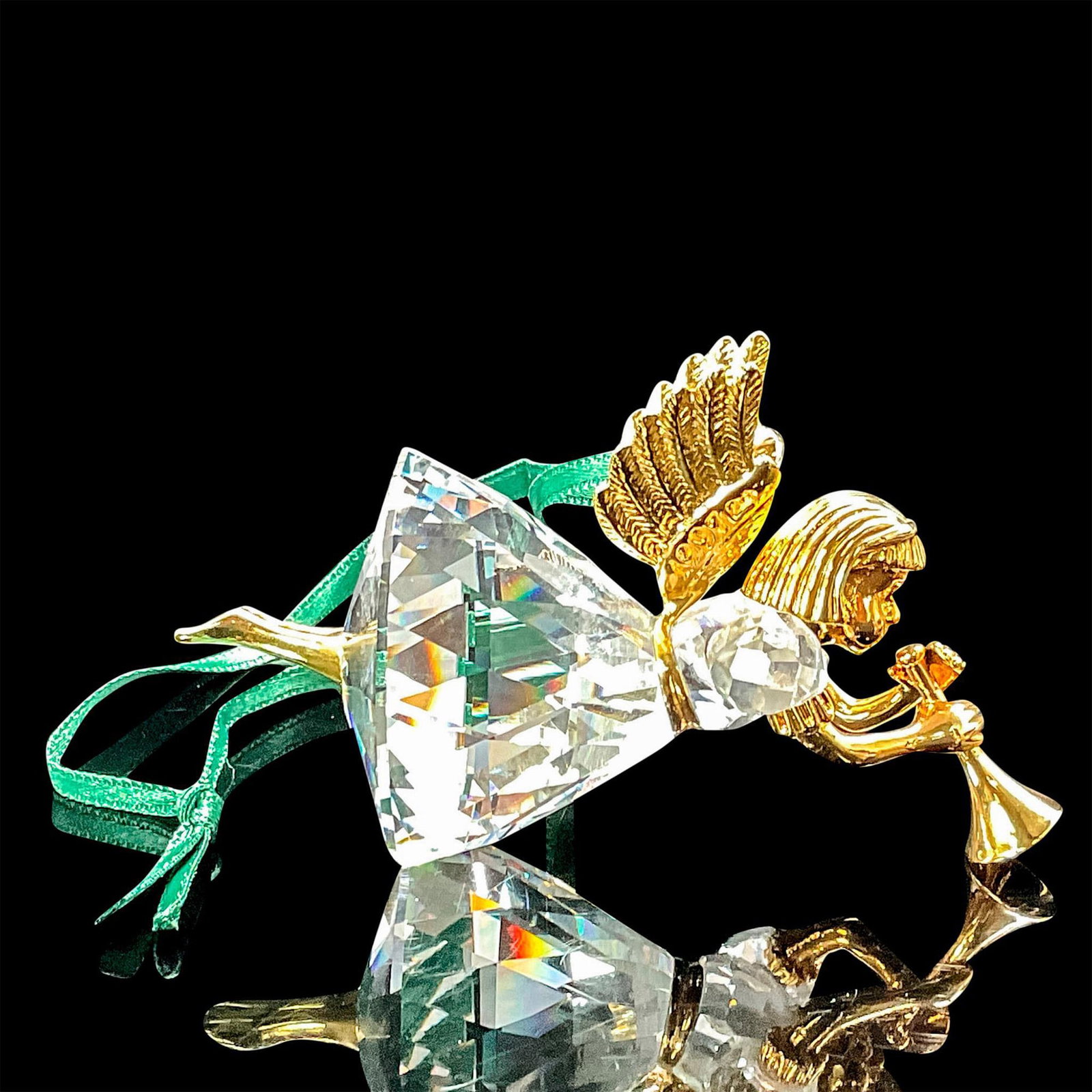 Swarovski Crystal Memories Ornament, Angel: Clear crystal angel with trumpet. Gold accents on body and wings, on green satin ribbon. Swarovski impressed backstamp. This item has its original box. Box measures: 3.75"L x 3.75"W x 3"H. Issued: 199