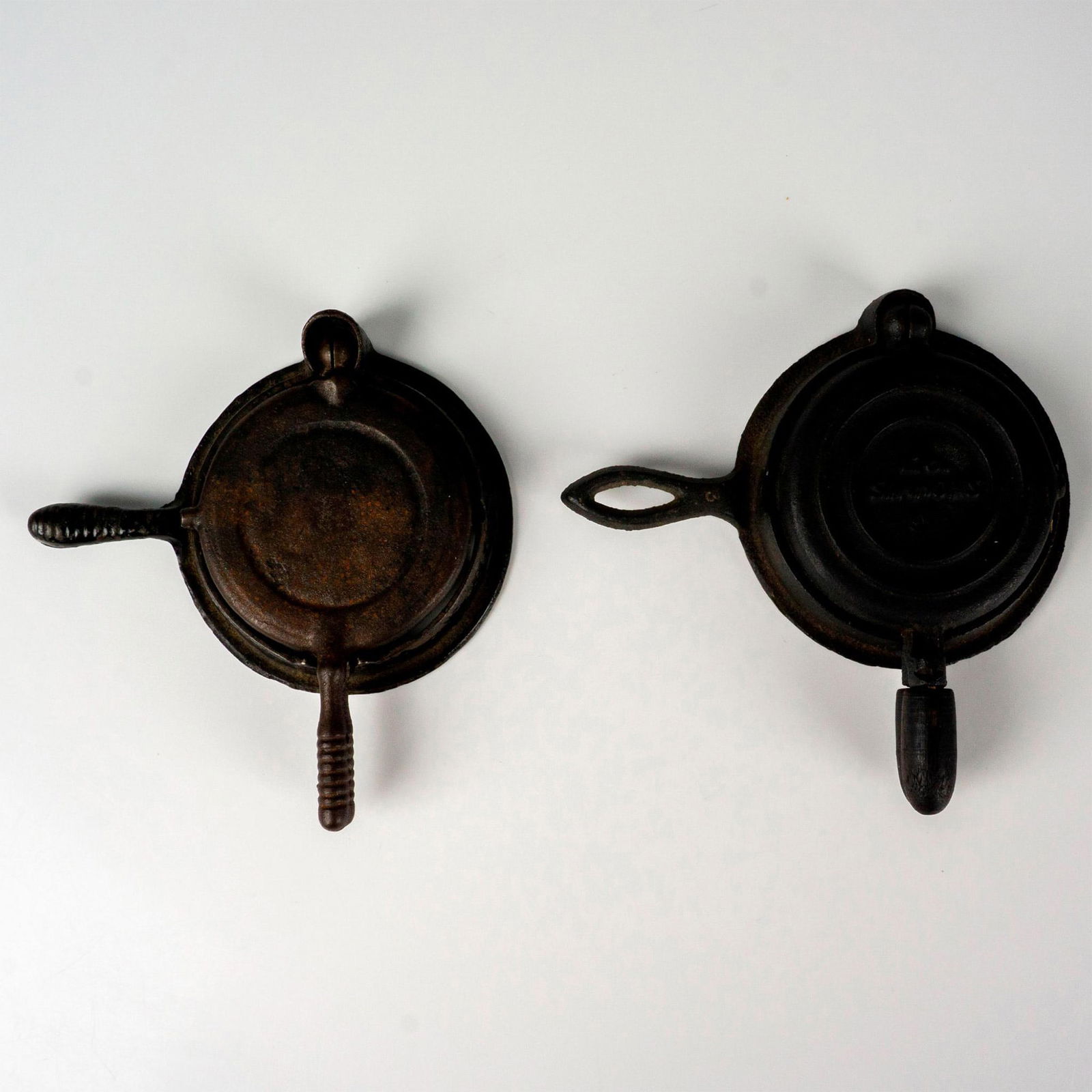 Pair of Mini Cast Iron German Waffle or Cookie Irons: Two delightfully small waffle irons in cast iron with decorative patterns. The iron separates into two pieces for easier removal or cleaning and includes the cooking base. Largest piece measures 7"L x
