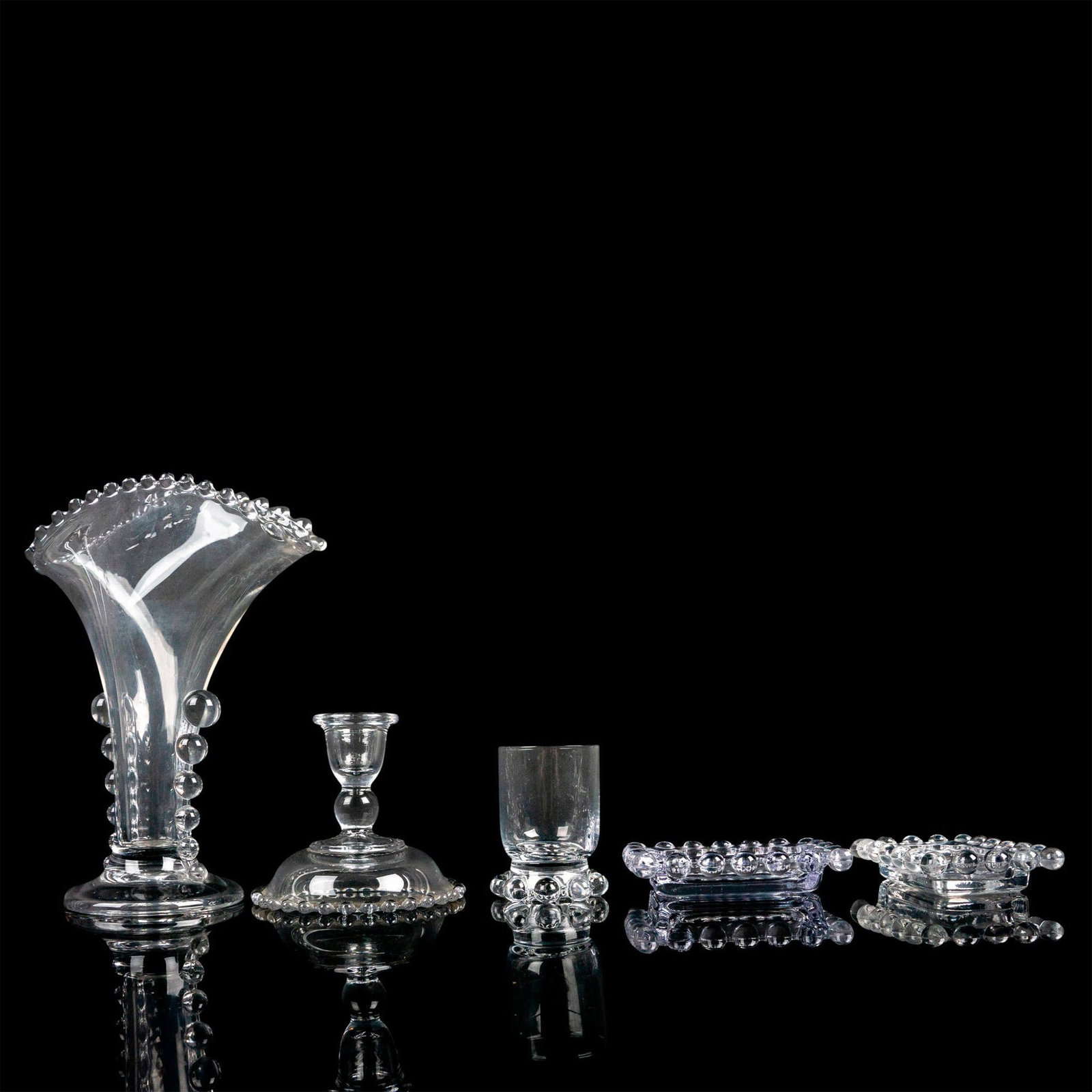 5pc Imperial Glass-Ohio Candlewick Decorative Objects: Includes 1 fan-shaped vase, 2 ashtrays, and 2 single candle holders. Clear with a beaded rim. Vase: 7.5"L x 3.5"W x 8.5"H. Ashtray: 4.25"L x 3"W x 0.75"H. Candlestick holder: 4.25"W x 3.75"H. Votive c