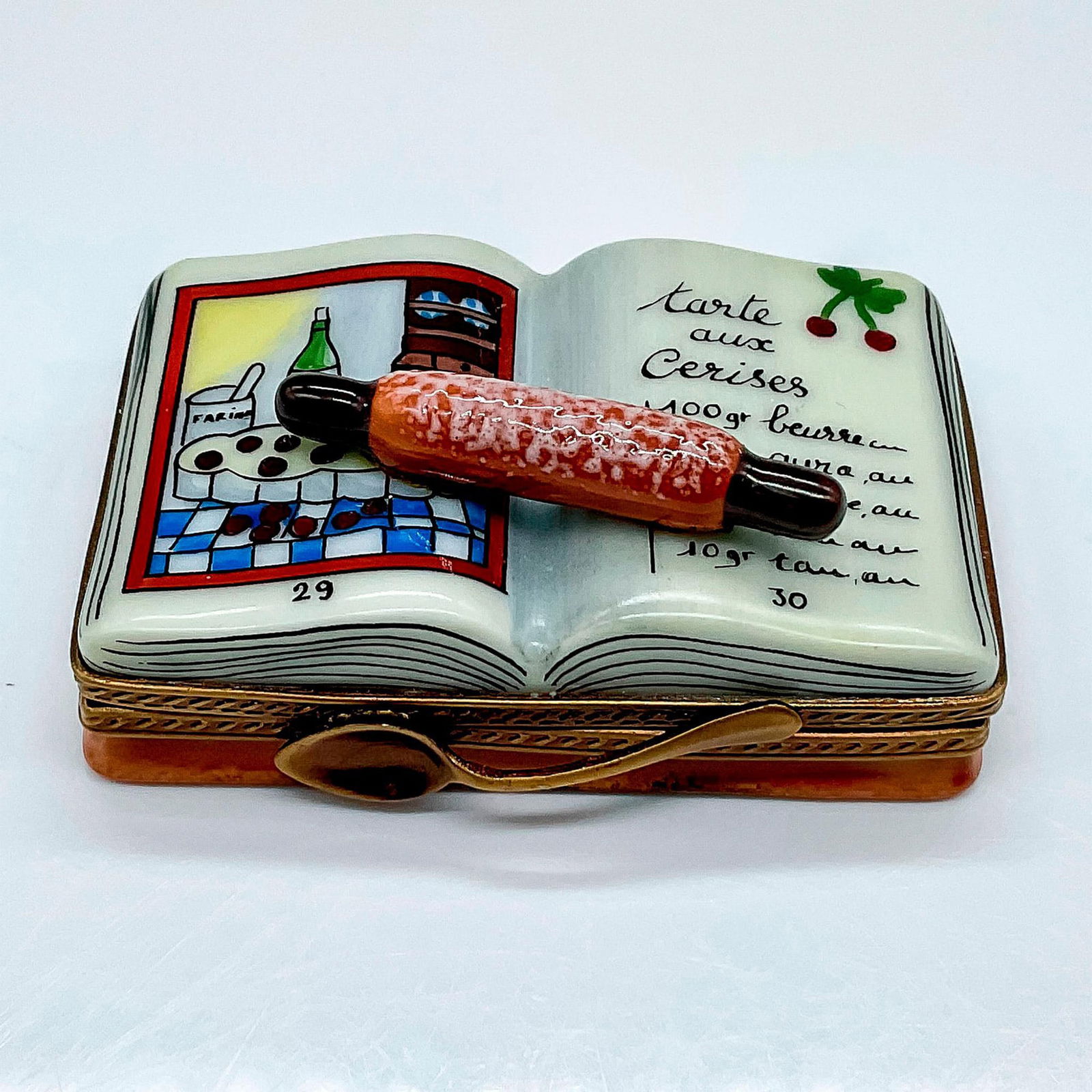 La Gloriette Limoges Porcelain Cookbook Box: Hand painted box modeled as an open cookbook with a rolling pin on. A rolled up napkin painted inside the box. La Gloriette Limoges France Peint Main marked on the interior. Issued: 20th century Dimen