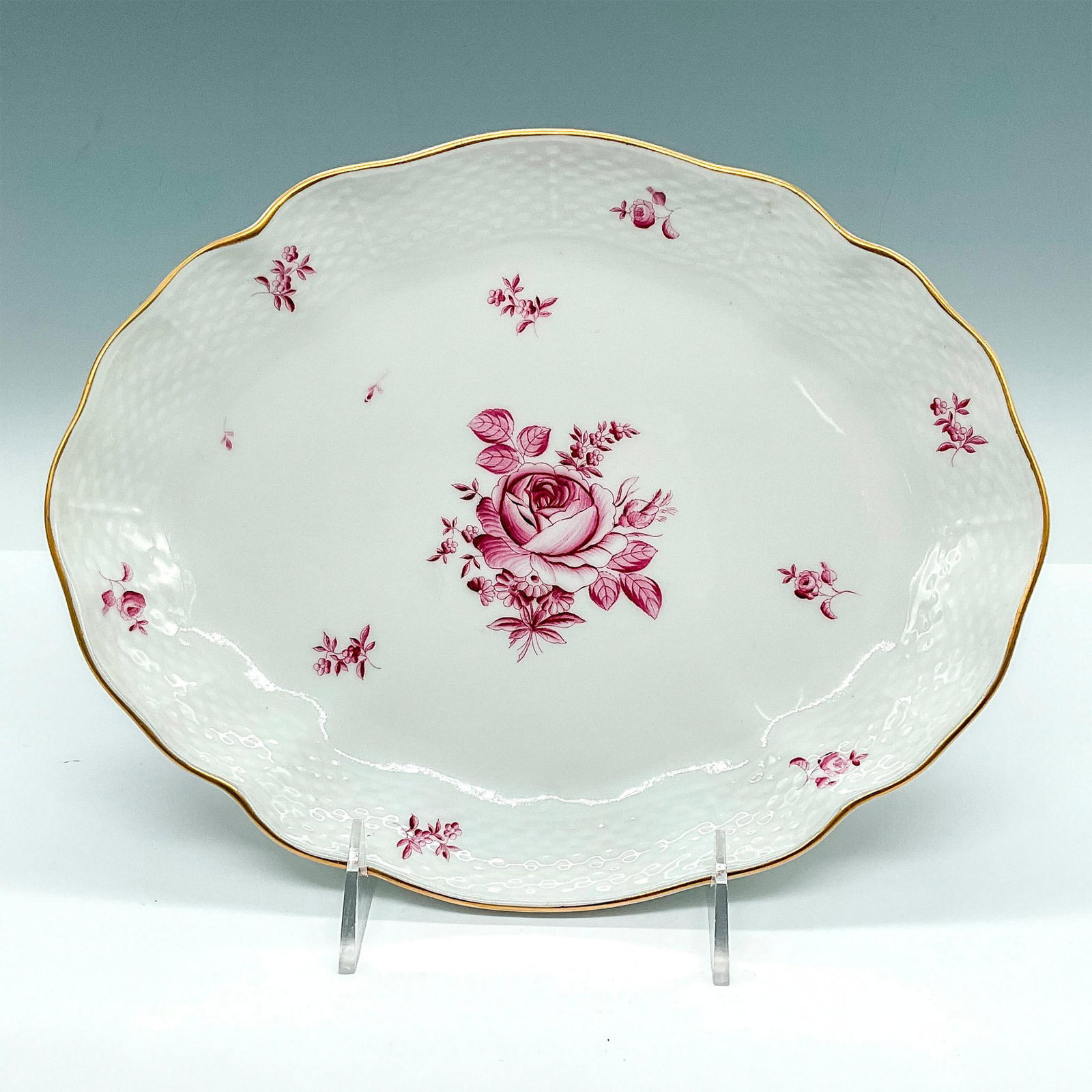 Herend Porcelain Gravy Boat Underplate: Hand-painted porcelain underplate with dark pink center rose design, basketweave textures, and golden trim applied to the scalloped rim. Herend backstamp. Issued: 20th c. Dimensions: 10"L x 8.25"W x 1