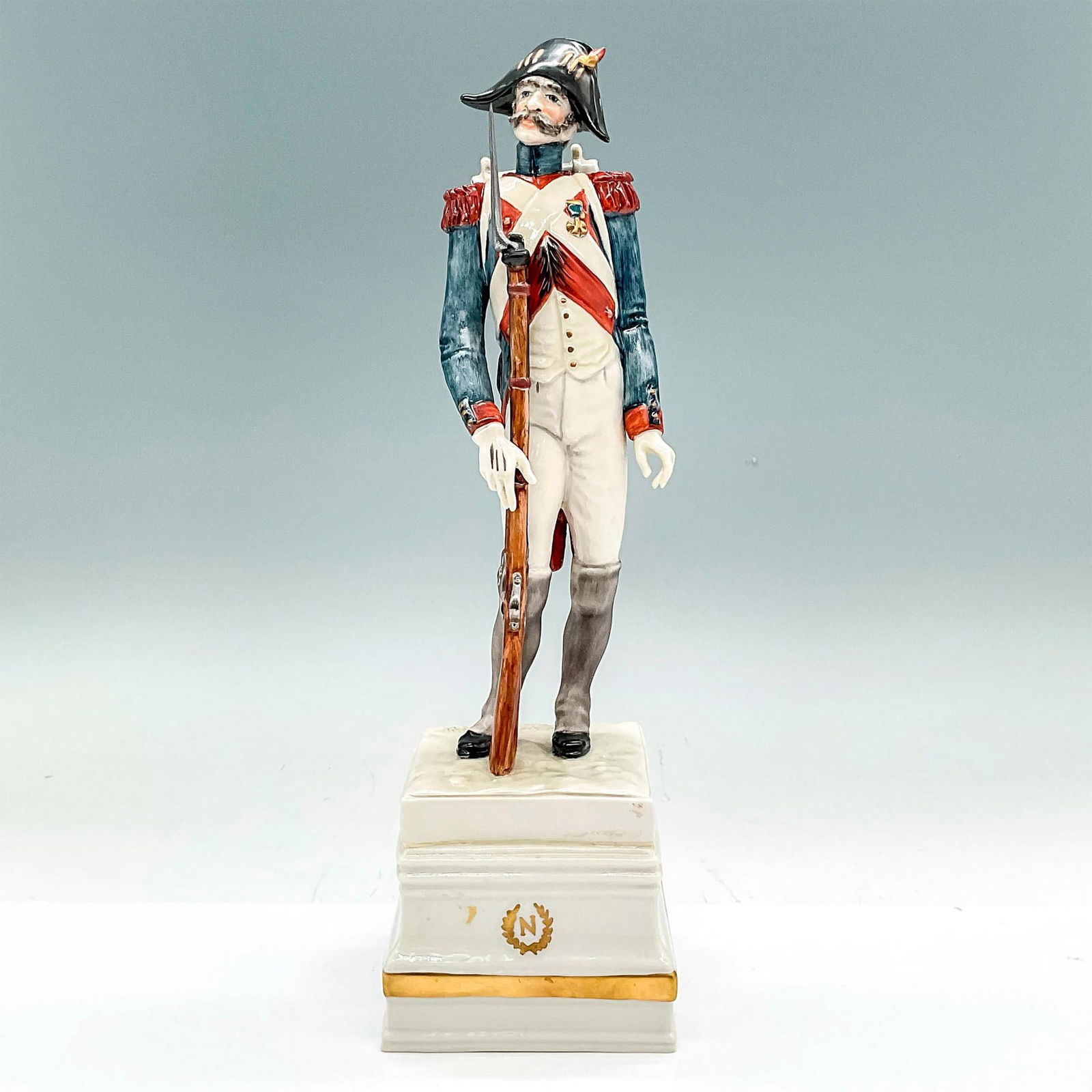 Cacciapuoti Porcelain Napoleonic Figurine, Veteran Rifle: A Guido Cacciapuoti figurine depicting Napoleonic era imperial French soldier on a raised porcelain pedestal with gilt N within a wreathed medallion to front, and name of piece inscribed to verso of p