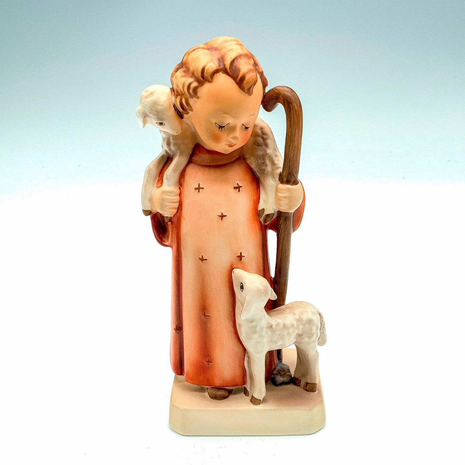 Goebel Hummel Figurine, Good Shepard: Matte porcelain, hand painted. Child in red robe standing with two lambs. M. I. Hummel inscribed on base. Goebel backstamp. Issued: 1979-1990 Dimensions: 2.75"L x 2.25"W x 6.5"H Manufacturer: Goebel H