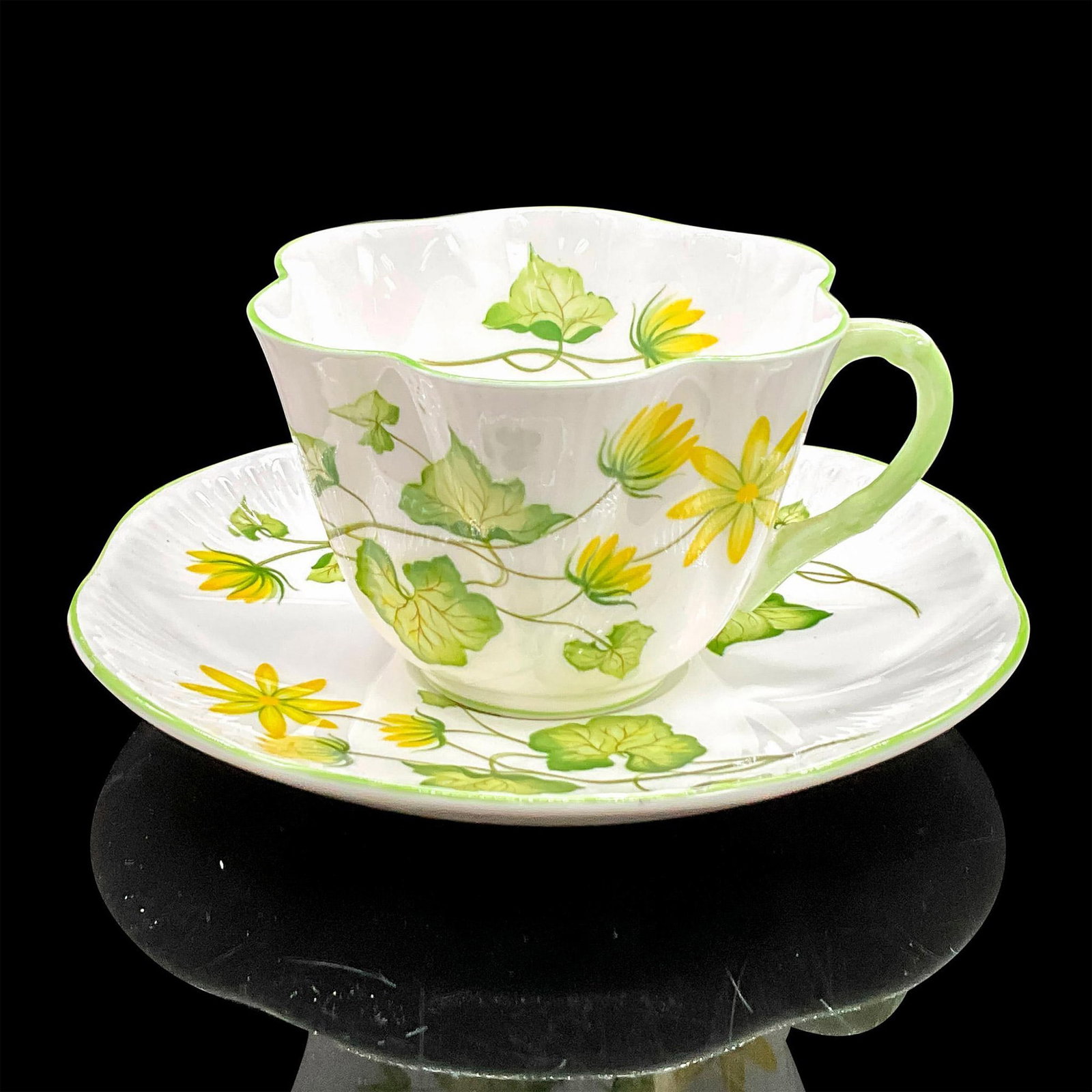 2pc Shelley England Cup and Saucer, Celandine: Vintage white bone china with bright yellow flowers, green rims. Dainty shape. Tea cup 4"L x 3.5"W x 2.5"H. Saucer 0.75"H x 5.75"dia. Shelley England backstamp. Manufacturer: Shelley Country of Origin