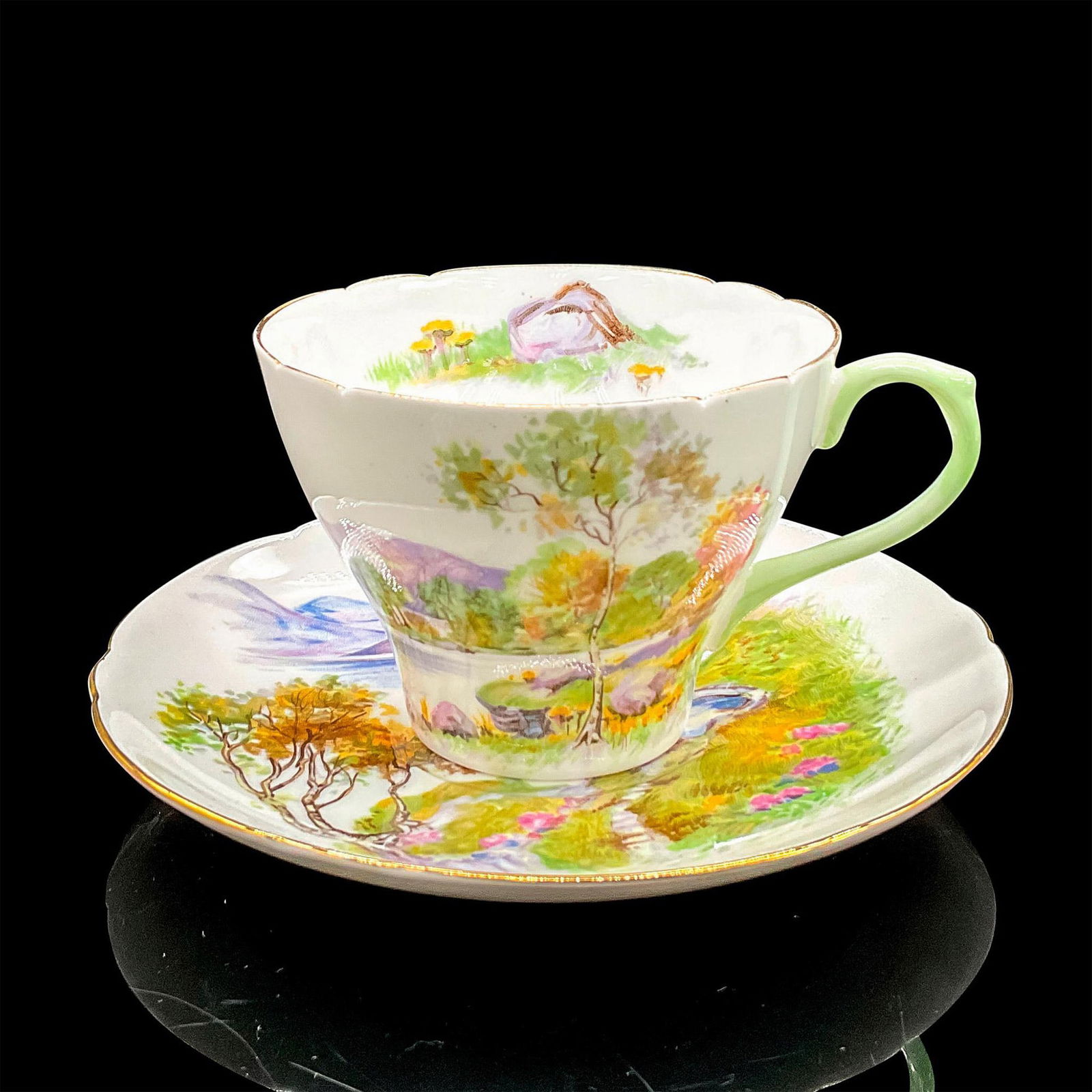 2pc Shelley England Cup and Saucer, English Lakes: Vintage white bone china with peaceful lakeside scene, gilt rims. New Cambridge shape. Tea cup 4"L x 3.5"W x 2.5"H. Saucer 0.75"H x 5.5"dia. Shelley England backstamp. Manufacturer: Shelley Country of