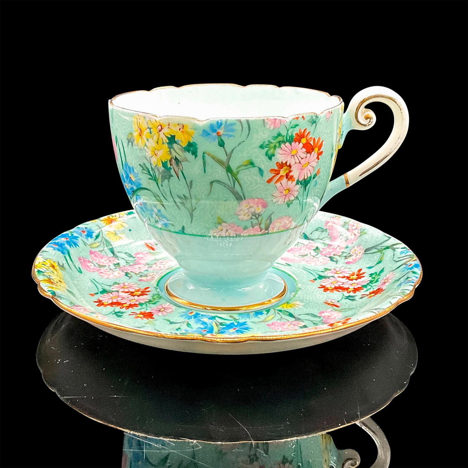 2pc Shelley England Cup and Saucer, Melody: Vintage robin's egg blue bone china with pink, blue, red and yellow flowers, gilt rims. Tea cup 4.25"L x 3.25"W x 2.75"H. Saucer 0.75"H x 5.5"dia. Shelley England backstamp. Manufacturer: Shelley Coun