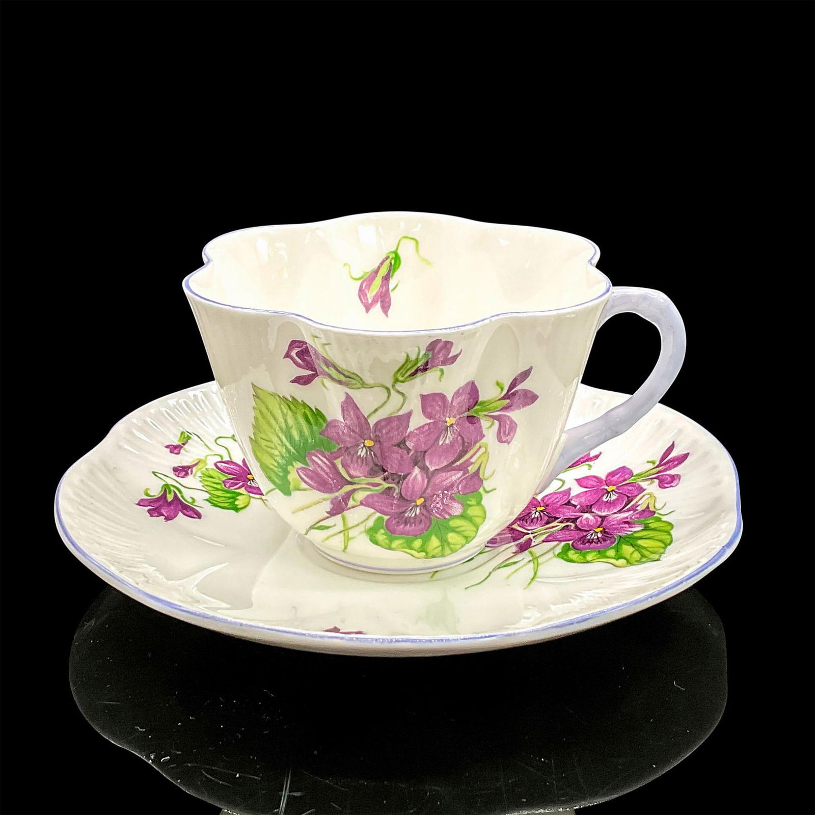 2pc Shelley England Cup and Saucer, Violets: Vintage white bone china with vibrant purple flowers, violet rims. Dainty shape. Tea cup 4"L x 3.5"W x 2.5"H. Saucer 0.75"H x 5.5"dia. Shelley England backstamp. Manufacturer: Shelley Country of Origi