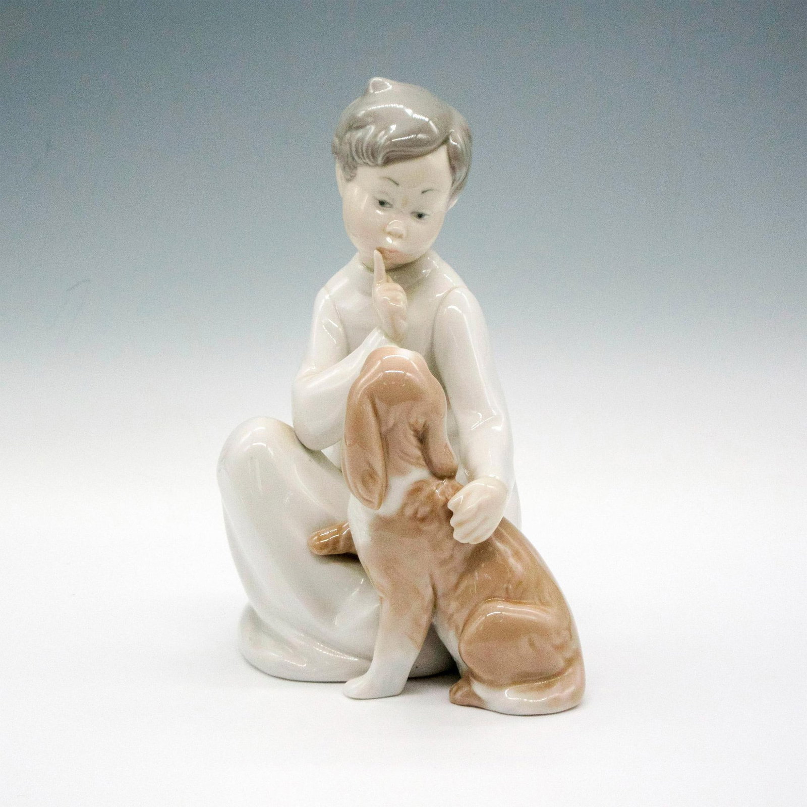 Boy With Dog 1004522 - Lladro Figurine: Porcelain collectable of a child and his pet. Glazed finish. Handmade piece. Lladro backstamp. Artist: Vincente Martinez Issued: 1970 Dimensions: 4"L x 5.75" W x 8"H Manufacturer: Lladro Country of O