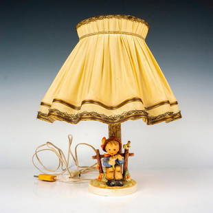 Goebel Hummel Table Lamp, She Loves Me Not: Electric figural lamps hand painted in matte finish muddled as a young boy seated holding a daisy. Includes original lamp shade. Goebel backstamp. Dimensions: 11.5"L x 11.5"W x 14"H Manufacturer: Goeb