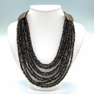 Cesaree Paris Ten Strand Dark Beaded Necklace: Ten strands of small dark opalescent bronze and black tone beads with two bronze pieces that have the Cesaree Paris stamp. Dimensions: 17"L Manufacturer: Cesaree Paris Country of Origin: France