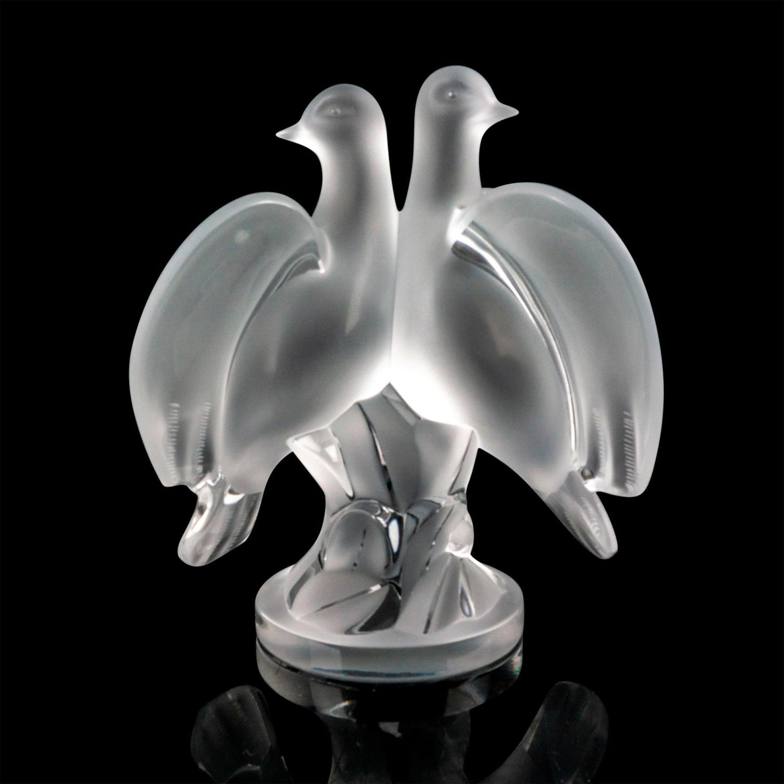 Lalique Crystal Figurine, Ariane Doves: A pair of frosted doves sitting side by side snuggling chest to chest on a clear round base. Signed Lalique France. Dimensions: 6.75"L x 5"W x 8.75"H Manufacturer: Lalique Country of Origin: France