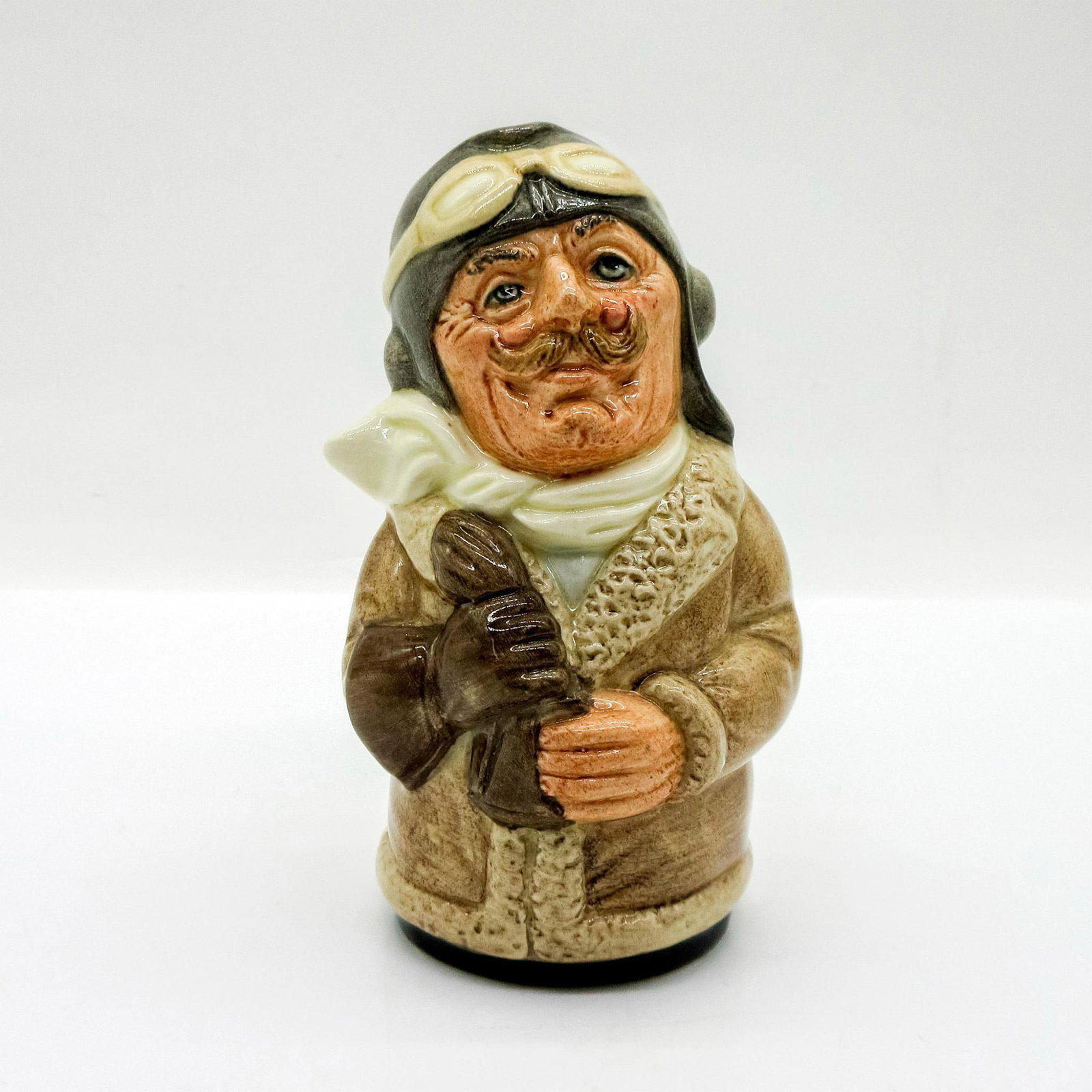Captain Prop the Pilot D6812 - Royal Doulton Toby Jug: Brown coat and gloves; grey cap; cream scarf. Series: The Doultonville Collection. Royal Doulton backstamp. Artist: William K. Harper Issued: 1989 - 1991 Dimensions: 4"H Manufacturer: Royal Doulton