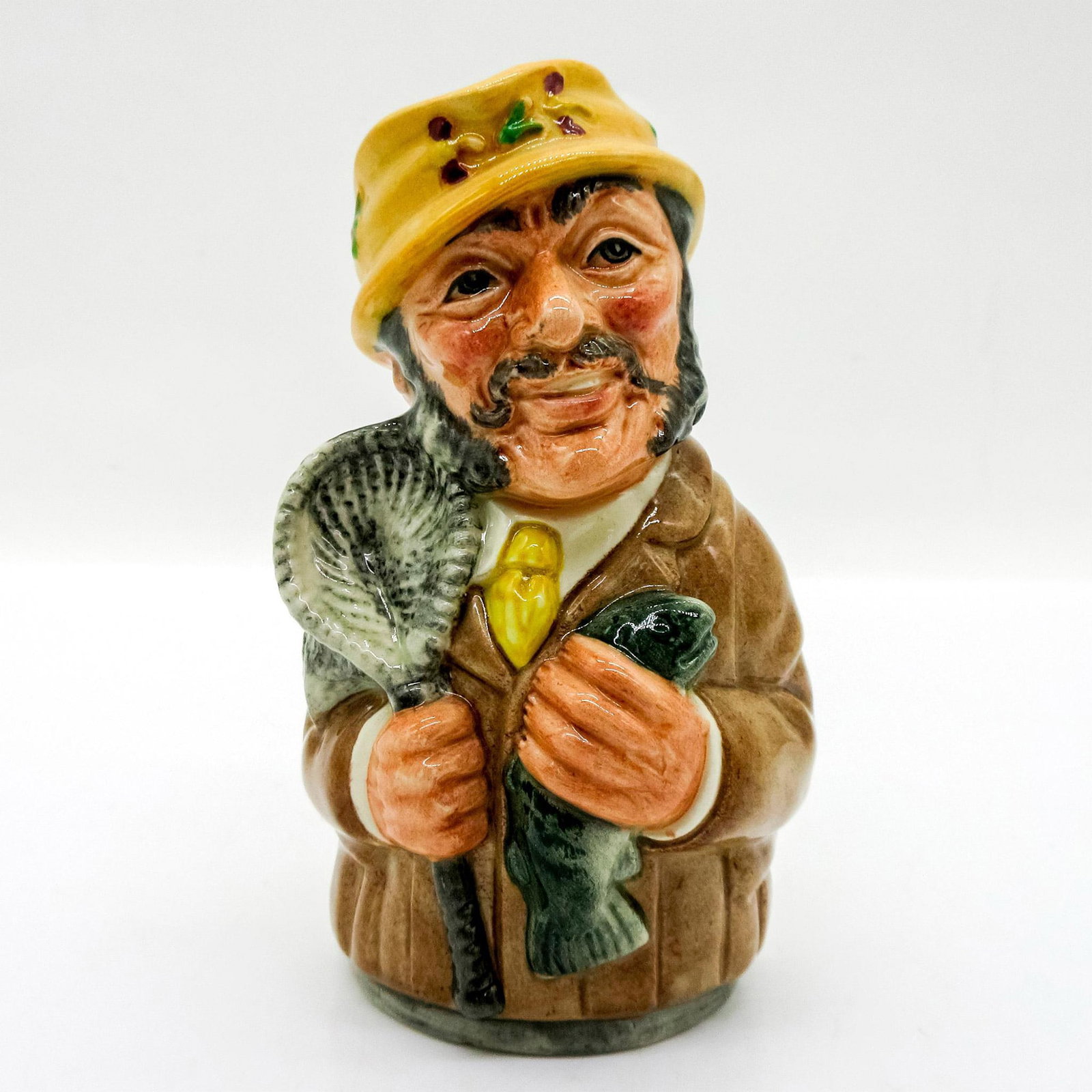 Fred Fly the Fisherman D6742 - Royal Doulton Toby Jug: Light brown coat; tan hat; grey fish and net. Series: The Doultonville Collection. Royal Doulton backstamp. Artist: William K. Harper Issued: 1986-1991 Dimensions: 4"H Manufacturer: Royal Doulton