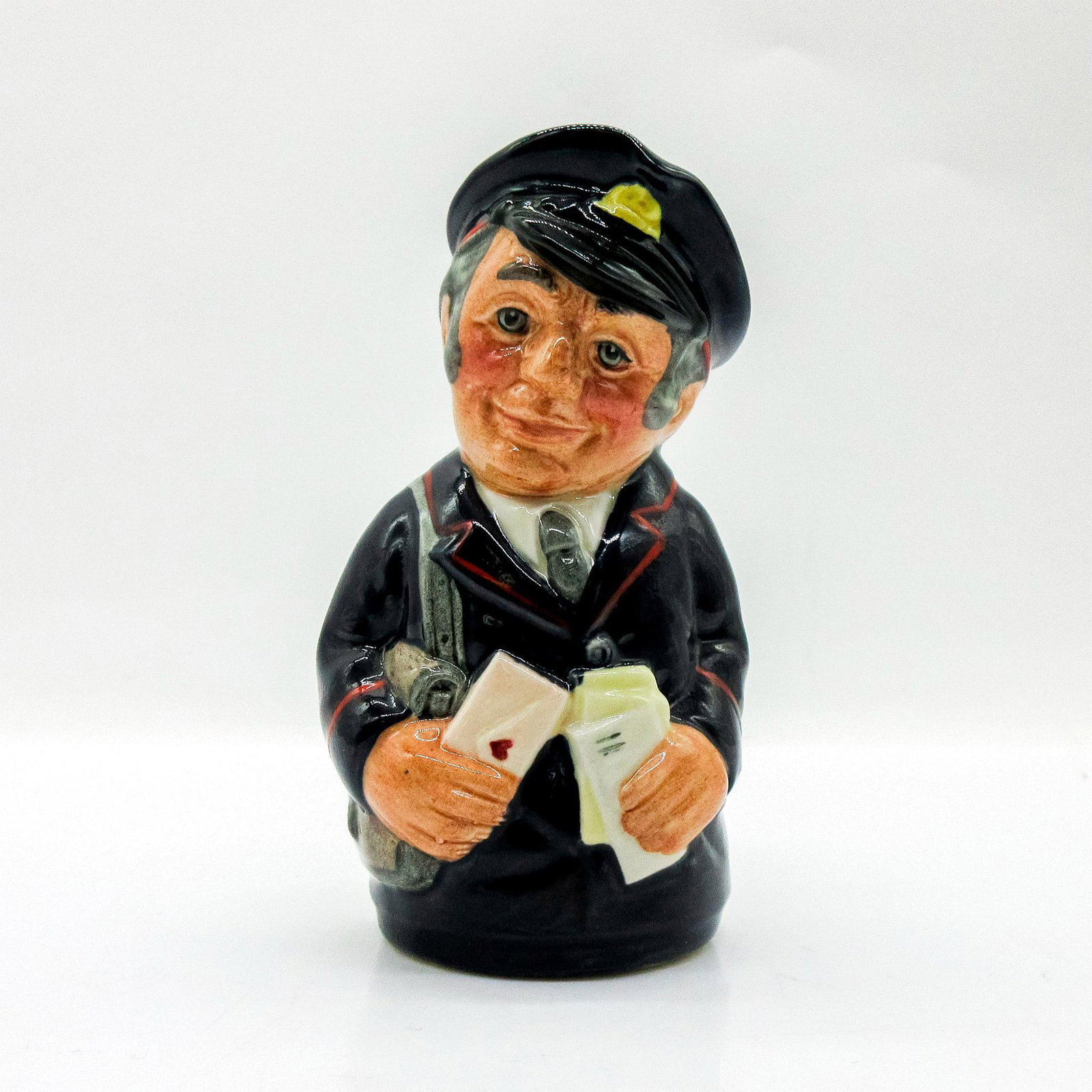 Pat Parcel the Postman D6813 - Royal Doulton Toby Jug: Dark blue uniform trimmed with red; grey postbag. Series: The Doultonville Collection. Royal Doulton backstamp. Artist: William K. Harper Issued: 1989 - 1991 Dimensions: 4"H Manufacturer: Royal Doult