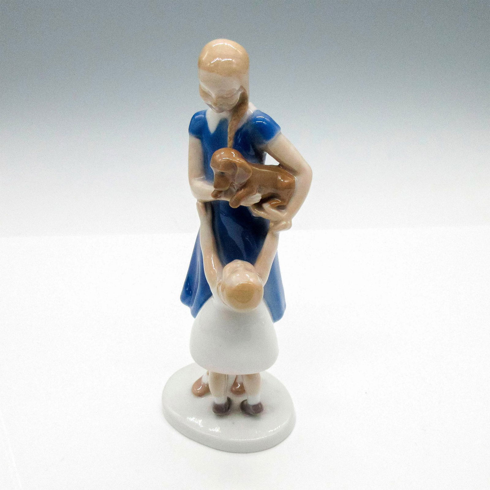 Bing & Grondahl Porcelain Figurine, Mother, Child and Puppy: Glossy figurine depicting a mother holding a dog in her arms as her young child begs to carry the little dog. Copenhagen figurine#2202. Bing & Grondahl backstamp. Dimensions: 3.50"L x 3"W x 7.50"H Iss