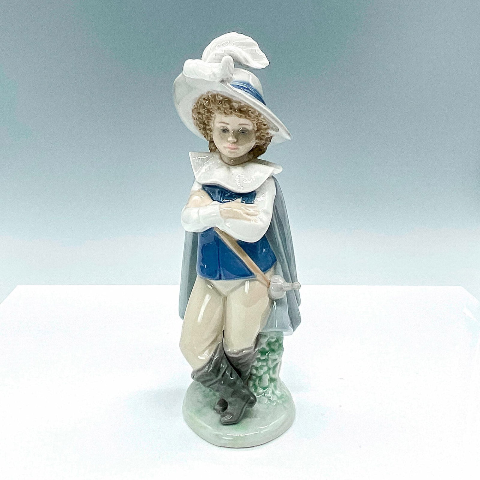 Nao Porcelain Figurine, Good Swordsman: Engaging glossy figurine of young swordsman dressed as a Musketeer. Nao backstamp. Dimensions: 3.5"L x 3.25"W x 9"H Manufacturer: Nao by Lladro Country of Origin: Spain