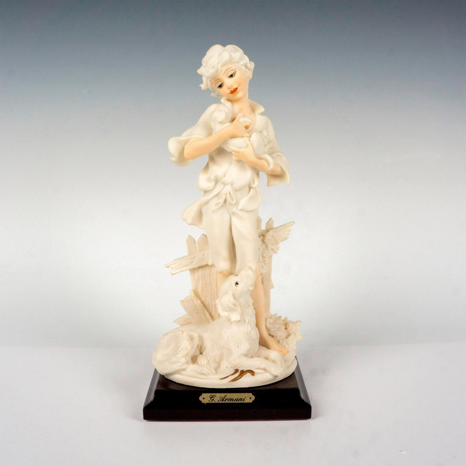 Florence Giuseppe Armani Figurine, Tenderness: Features a lady holding a puppy in arms; standing on a squared wooden base. G. Armani golden plate on wooden base. Giuseppe Armani backstamp. Artist: Giuseppe Armani Dimensions: 4"L x 4"W x 9.25"H Iss