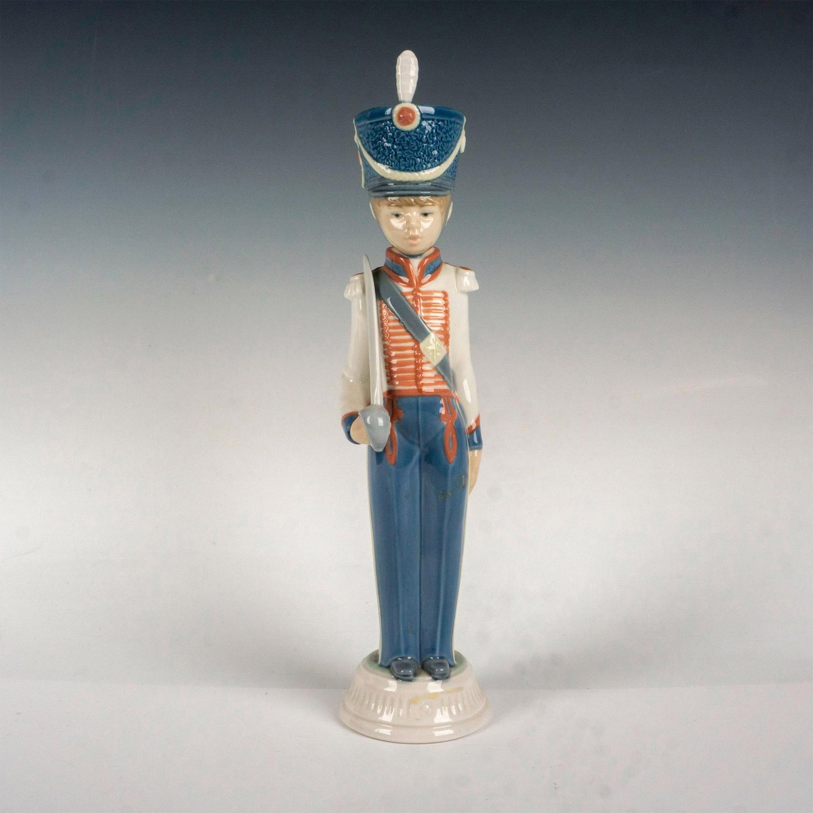 Cadet Captain 1005404 - Lladro Porcelain Figurine: Glossy finish; Lladro backstamp. Artist: Vicente Martinez Issued: 1987 - 1989 Dimensions: 12.5"H Manufacturer: Lladro Country of Origin: Spain