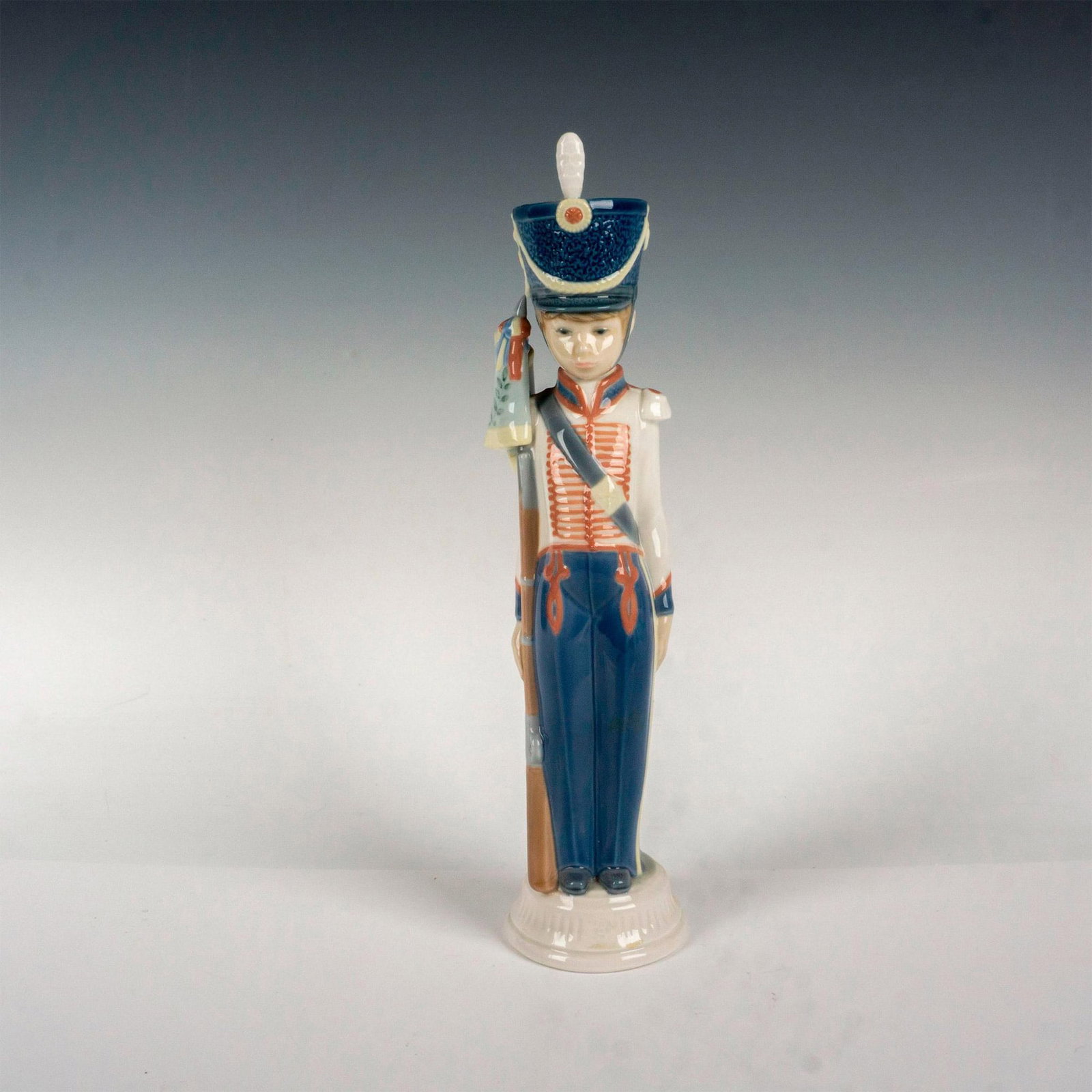 Flag Bearer 1005405 - Lladro Porcelain Figurine: Glossy finish; Lladro backstamp. Artist: Vicente Martinez Issued: 1987 - 1989 Dimensions: 12.5"H Manufacturer: Lladro Country of Origin: Spain