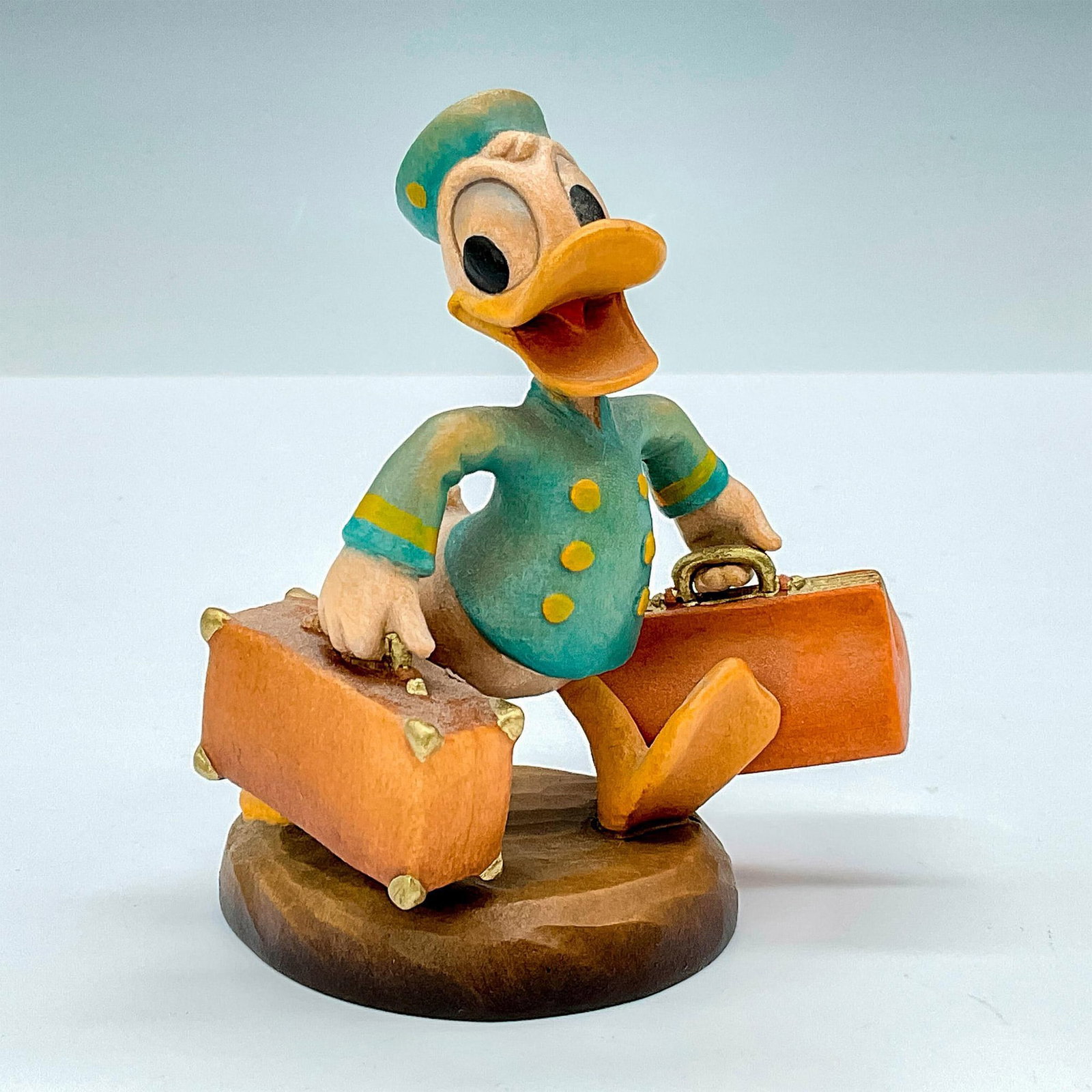 Anri Club Walt Disney Wood Figurine, Bellboy Donald: Adorable painted wooden figurine of Donald Duck as a bellboy in 1942 movie. In hues of earthy green, blue, tan and yellow. Anri metal logo emblem affixed to base. The Walt Disney Company backstamp on 