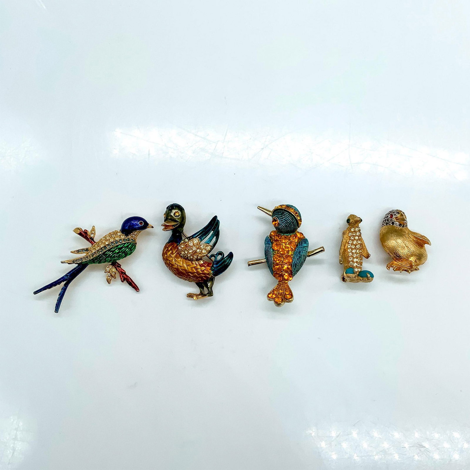 5pc Gold Metal and Rhinestone Costume Bird Brooch Pins: Jeanne gold tone penguin with rhinestones and turquoise feet measures 1.25"H. Duck pin with rhinestones measures 1.75"H. Nettie Rosenstein small bird pin measures 1.25"H. Colorful swallow bird pin mea
