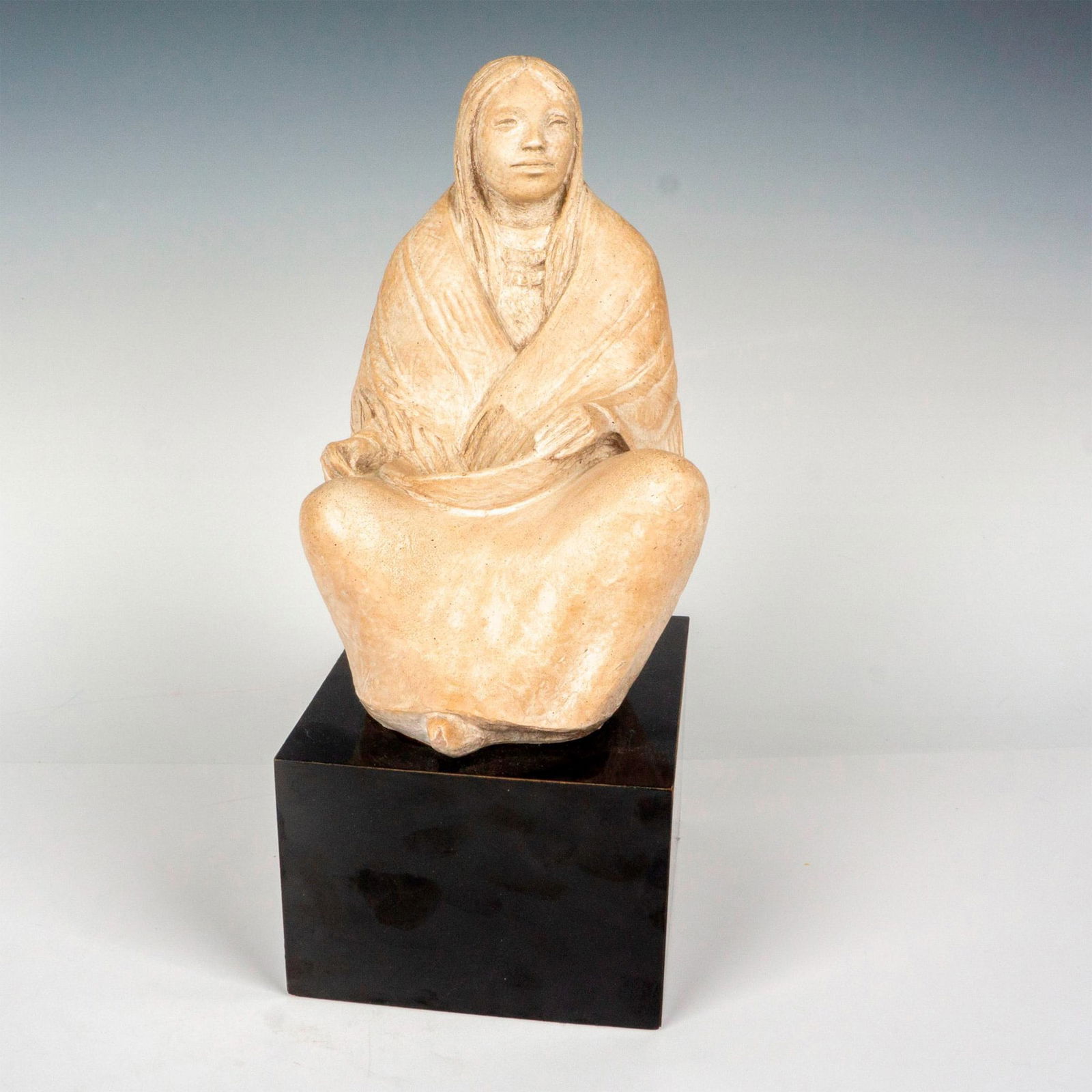Austin Productions James Marshall Sculpture, Seated Squaw: A sculpted figure of a woman draped in a shawl, resting a basket on her lap. Attached to a black base. Austin Productions 1983 carved on the back of the figure. Artist: James Marshall Issued: 1983 Dim
