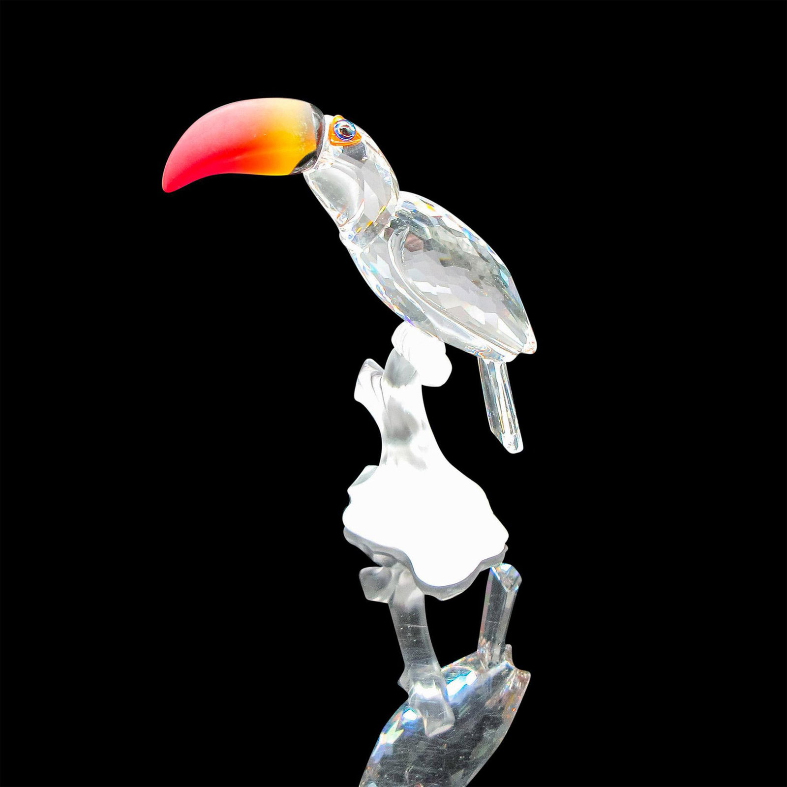 Swarovski Silver Crystal Figurine, Toucan: Part of the Feathered Beauties collection. Figural has fire opal crystal beak with blue iridescent eyes, sitting on a frosted branch. Swarovski backstamp. 7621000006. This item has its original box: 4