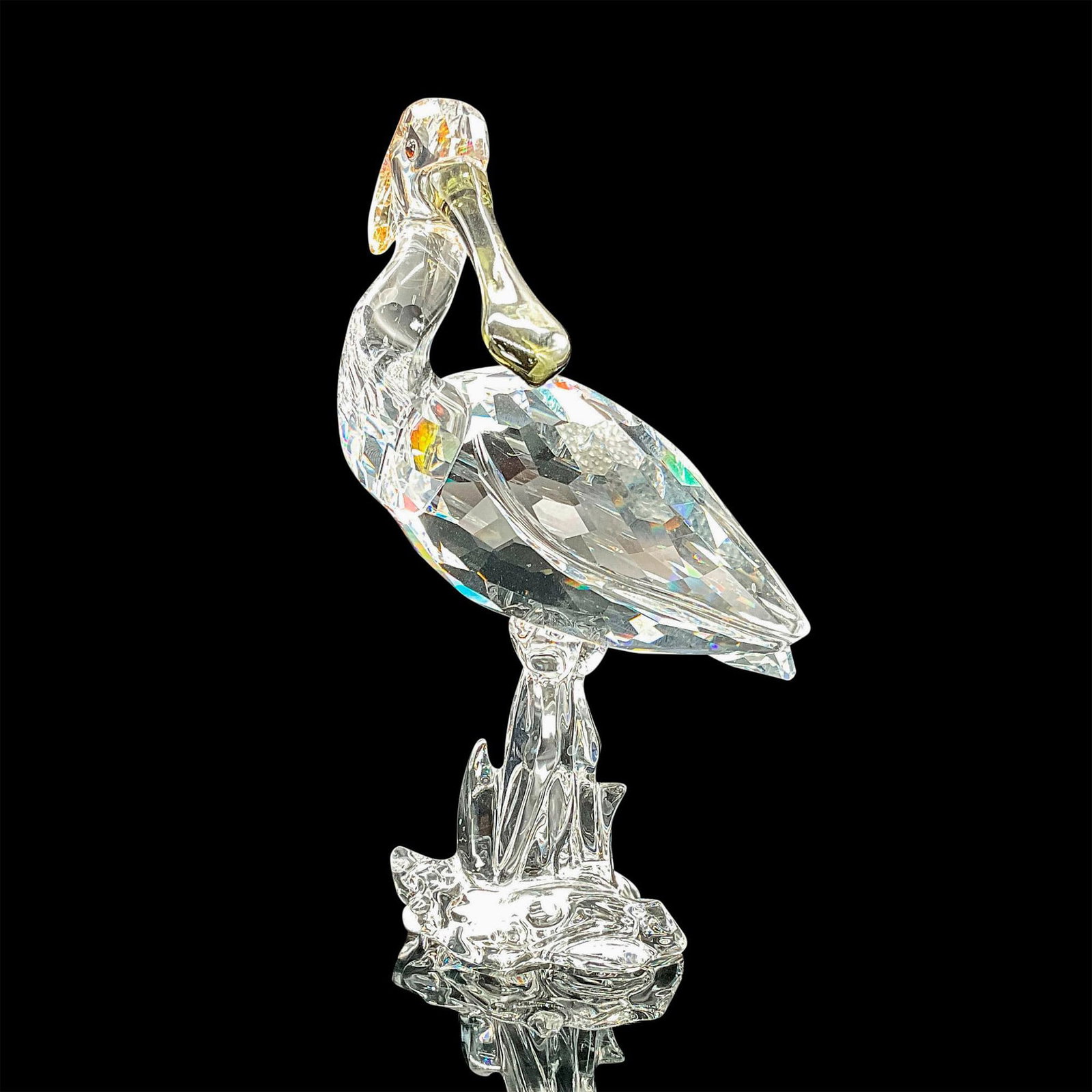 Swarovski Crystal Figurine Spoonbill: Feathered Beauties Collection. Body made of faceted clear crystal with black diamond crystal beak, accents in golden shade crystal. This item has its original box which measures 5"L x 8"W x 8"H. Swaro