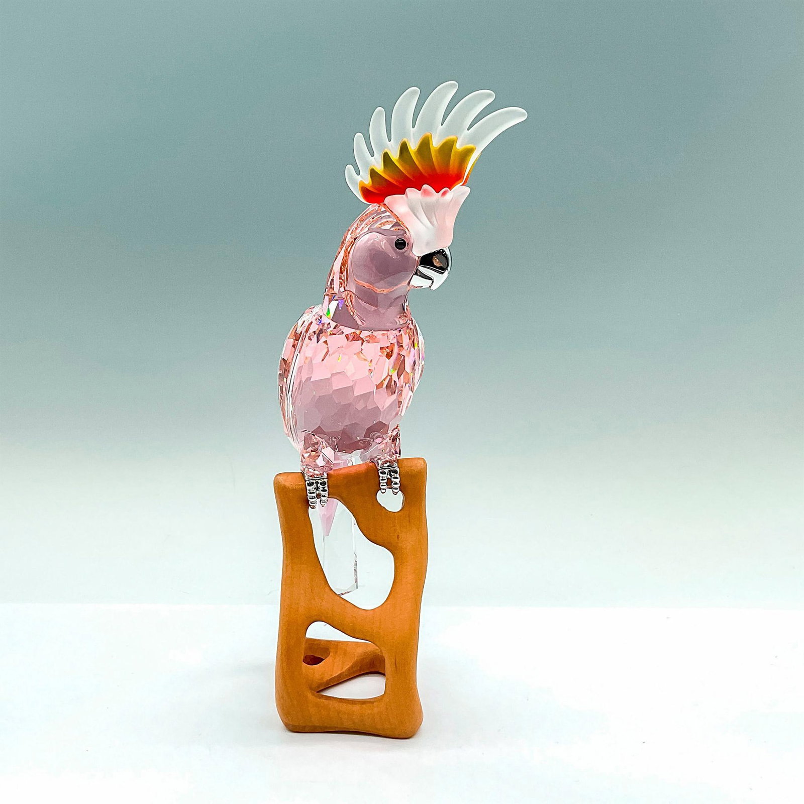 Swarovski Crystal Figurine, Cockatoo Red: Paradise Birds collection; made from a Kakadu red crystal with frosted white and orange feathers, black crystal eyes, and chrome beak and talons. Perched on a wooden base. Swarovski etched mark on the
