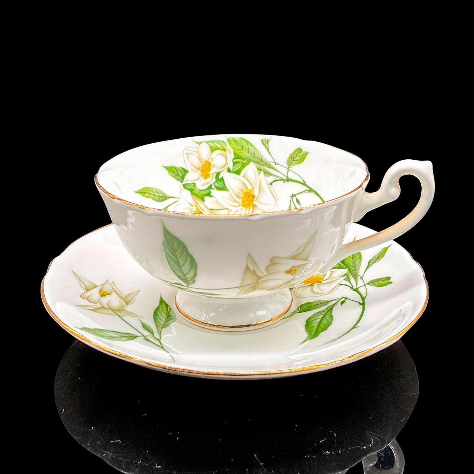 2pc Shelley England Cup and Saucer, Syringa: White bone china with lovely white flowers, yellow pistils and green leaves; gilt rims. Lincoln shape. Tea cup 5"L x 4"W x 2.25"H. Saucer 0.75"H x 5.75"dia. Shelley England backstamp. Manufacturer: Sh
