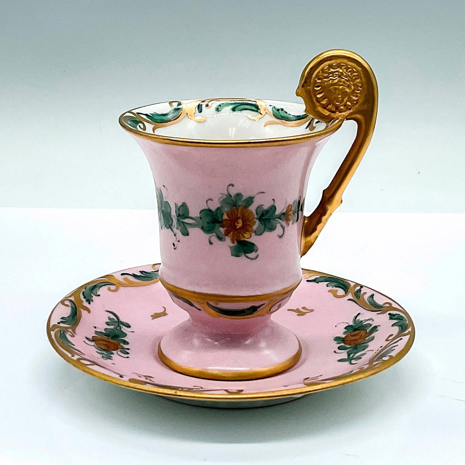 Jordan Marok Co. French Demitasse Cup and Saucer: Hand painted beautiful matte finish pink cup and saucer adorned with gold-colored roses. Gilded handle with an embossed relief of a face. Hand Painted Made in France For Jordan Marok Co. Cup: 3.5"