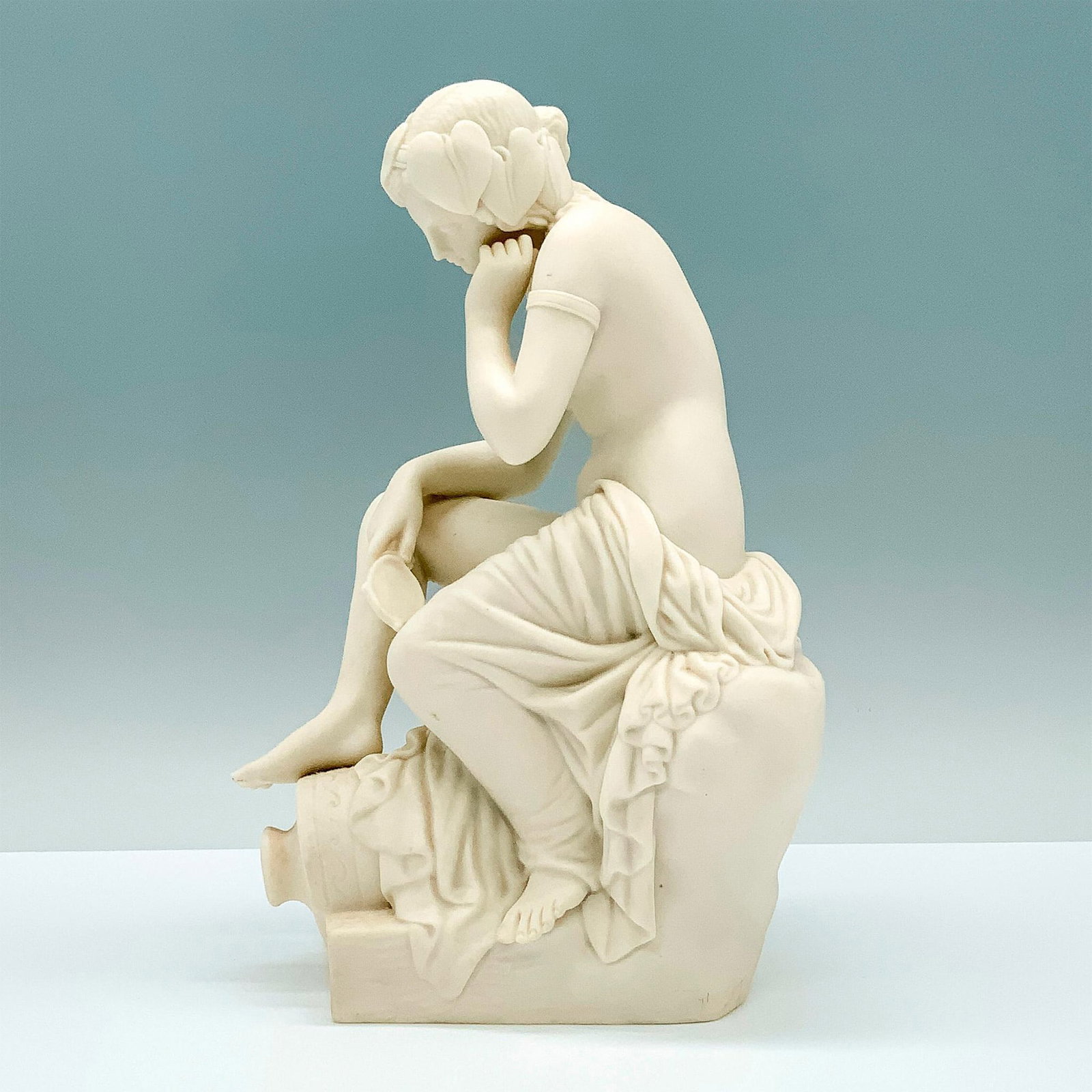 Copeland Parian Figure of Nude Seated Woman: A figure of a naked woman with a blanket wrapped around her leg and backside sitting on a ledge with her foot on top of a vase and a frog next to her. Copeland backstamp. Dimensions: 5.75"L x 4.5"W x 