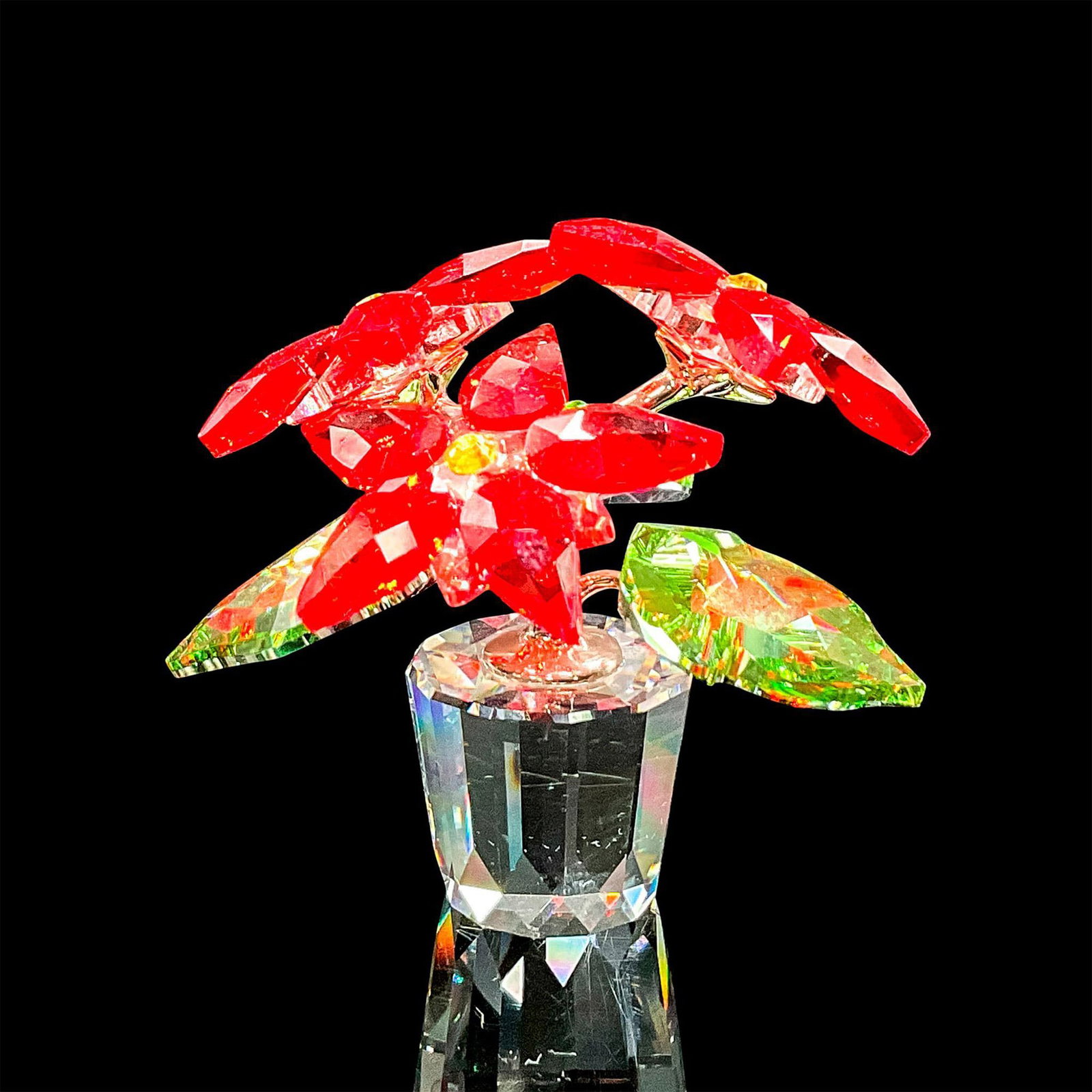 Swarovski Crystal Figurine, Poinsettia: Dazzling clear crystal figure of a potted poinsettia plant with vibrant red petals and green leaves. Includes original box 4.25"L x 4.5"W x 3.25"H. Dimensions: 2"L x 1.75"W x 1.5"H Manufacturer: Swaro