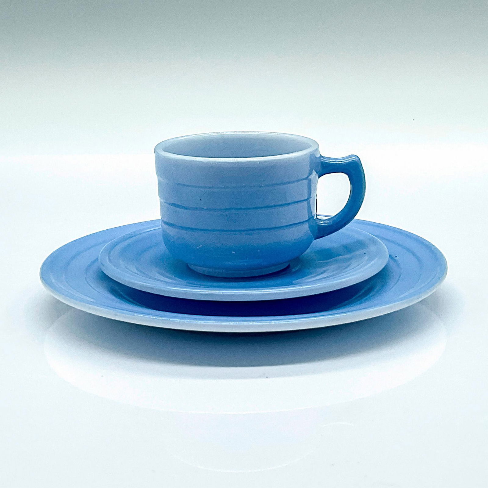 Hazel Atlas Glass Child Tea Cup Trio Set, Little Hostess: A vintage pastel cornflower-blue set; includes teacup, saucer, and snack plate. Cup: 2.75"L x 2"W x 1.75"H. Saucer: 0.75"H x 3.75"dia. Snack plate: 0.5"H x 5.25"dia. Manufacturer: Hazel Atlas Country