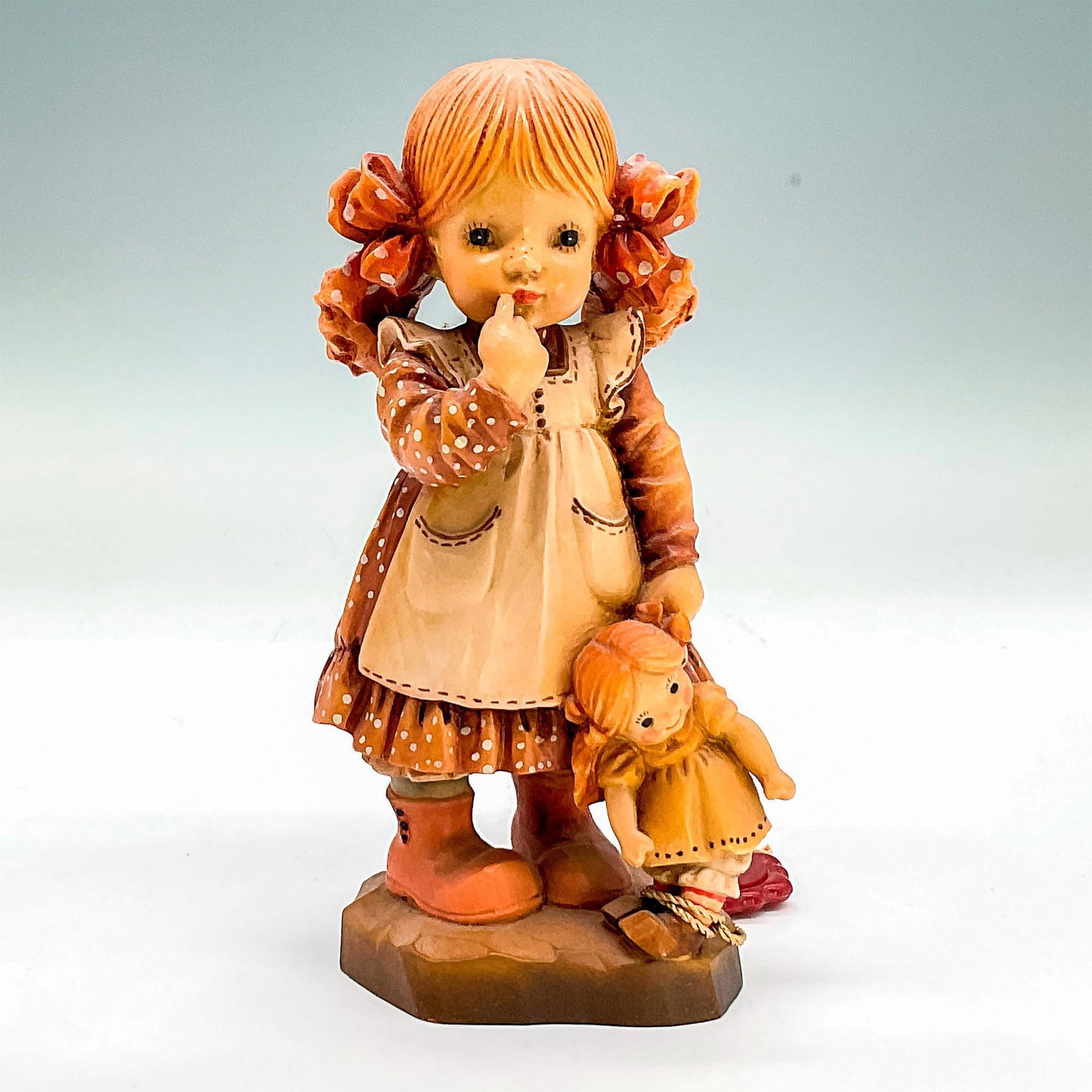 Anri Italy Wood Carved Figurine, Bedtime: Charming painted figure of a young girl holding her doll. In hues of earthy orange, tan and brown. Anri metal logo emblem affixed to base. Design Valentine backstamp. Sarah Kay engraved to back of bas
