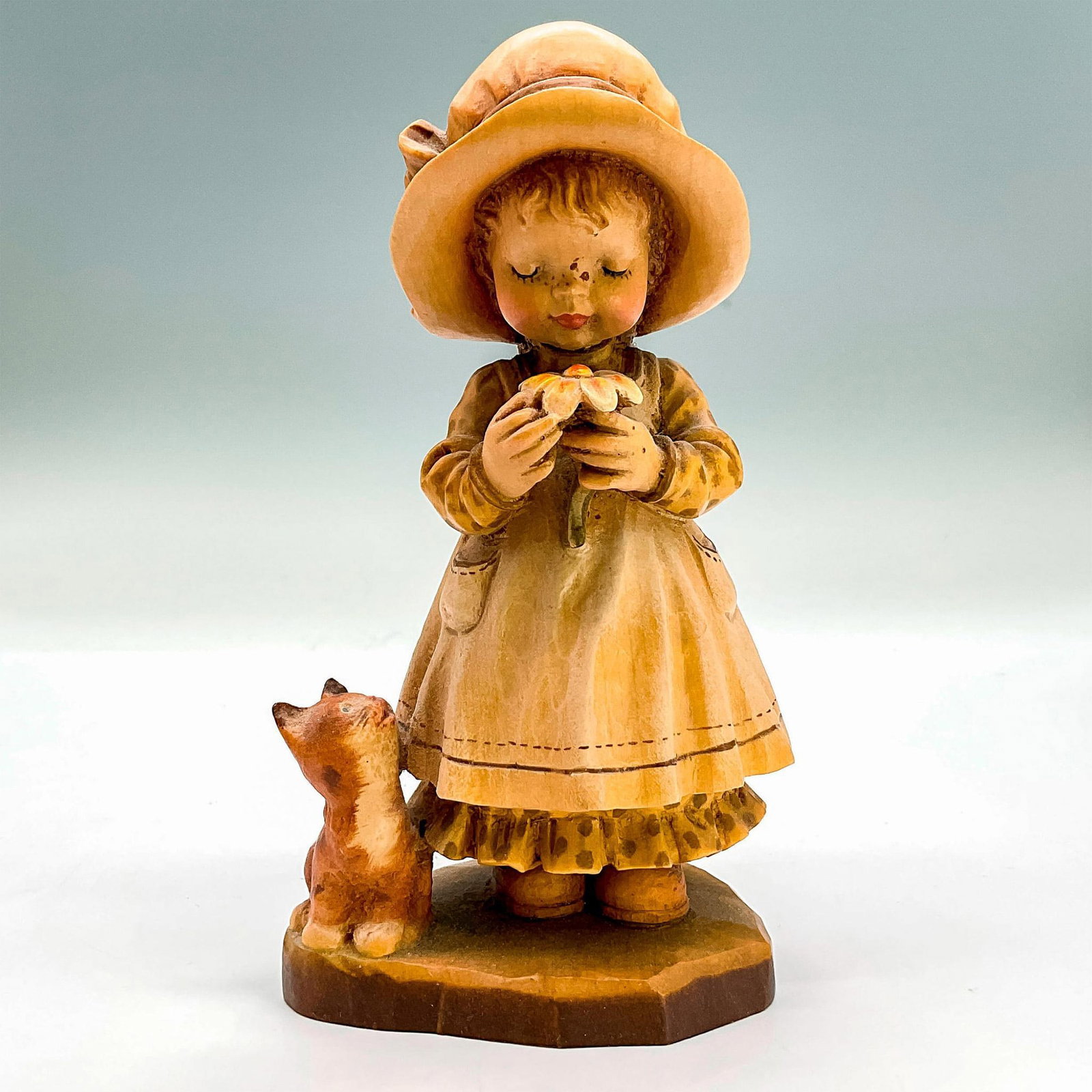 Anri Italy Wood Carved Figurine, Daydreaming: Cheerful painted figure of a young girl looking at a flower while her little cat looks up at her. In hues of earthy orange, yellow, tan and brown. Anri metal logo emblem affixed to base. Design Valent