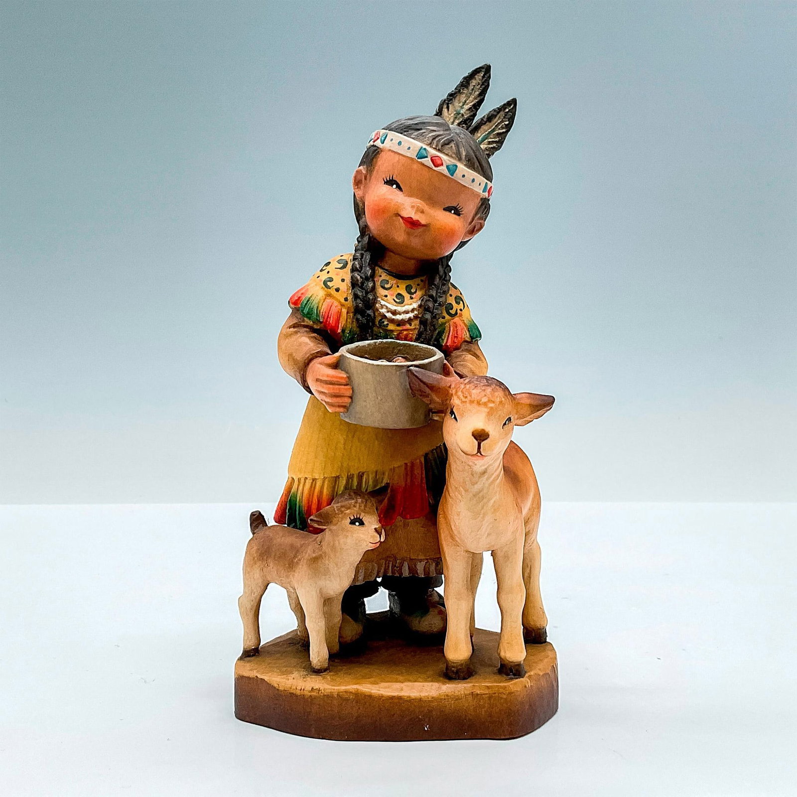 Anri Italy Wood Carved Figurine, Peace Maker: Cheerful painted figure of a young Native American girl holding a bowl with two lambs next to her. In hues of earthy orange, yellow, green, tan and brown. Anri metal logo emblem affixed to base. J Fer