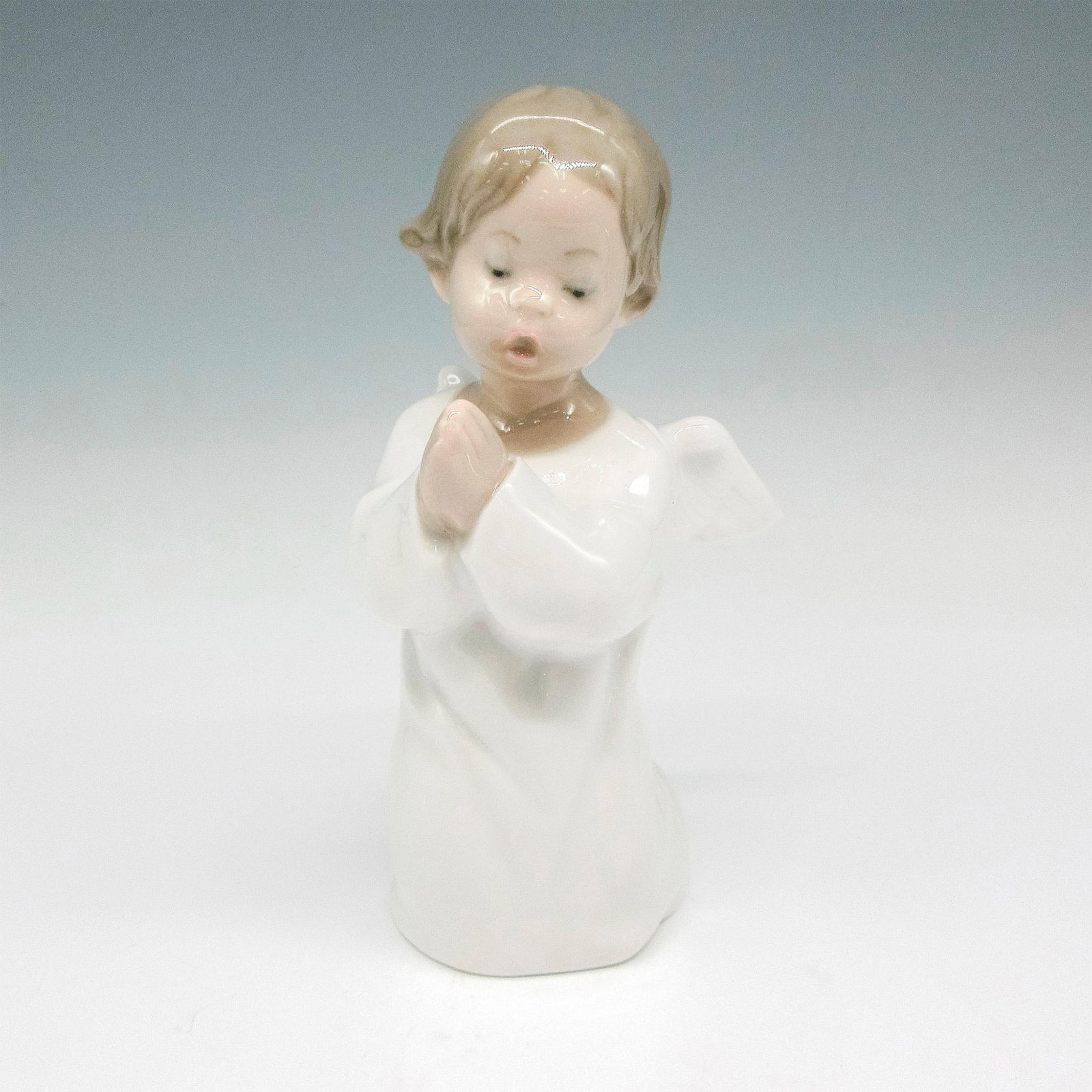 Angel Praying 1004538 - Lladro Porcelain Figurine: Glossy finish; Lladro backstamp. Artist: Fulgencio Garcia Issued: 1969 Dimensions: 5"H x 3.25"W Manufacturer: Lladro Country of Origin: Spain