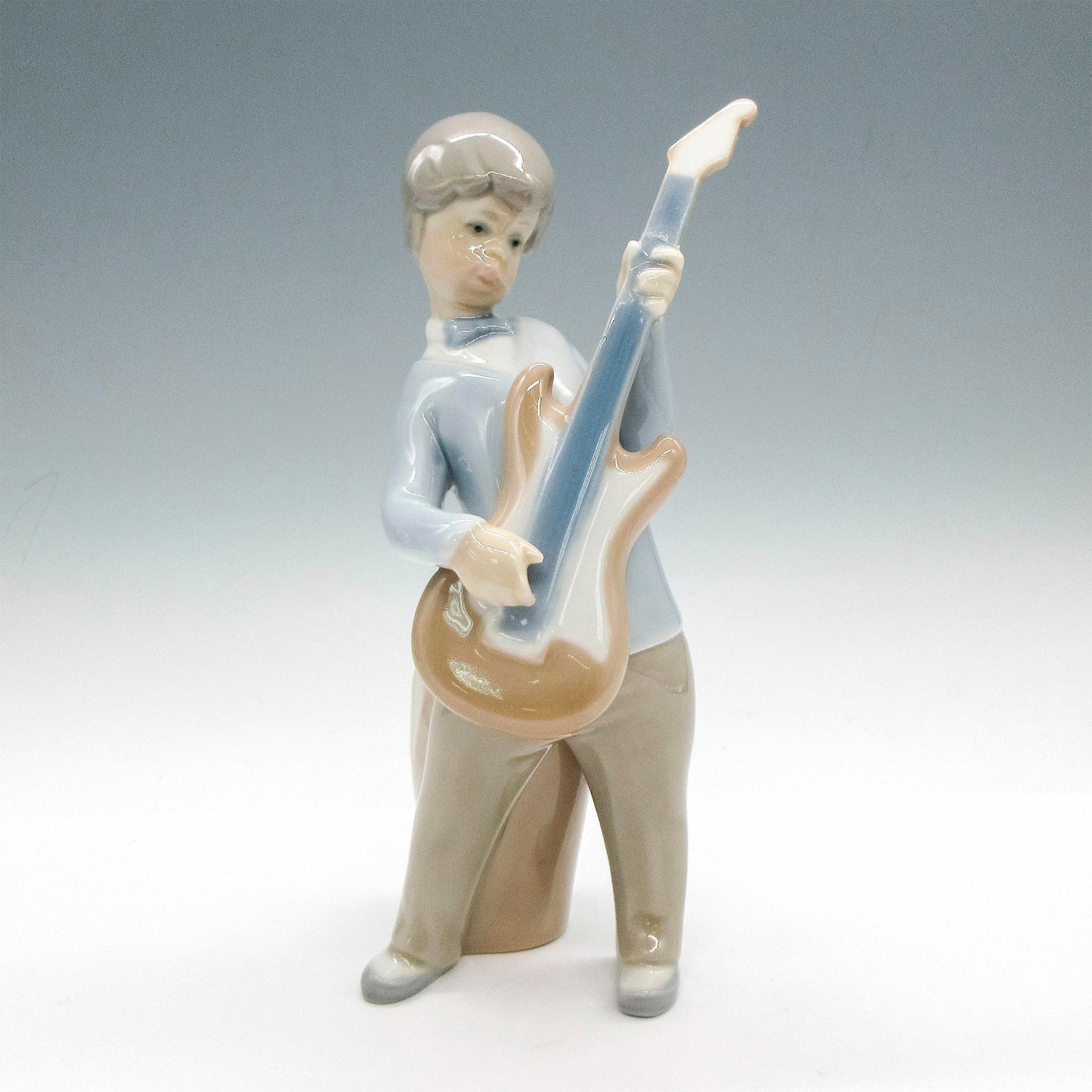 Boy With Guitar 1004614 - Lladro Porcelain Figurine: Glossy finish; Lladro backstamp. Artist: Juan Huerta Issued: 1969 - 1979 Dimensions: 7.5"H Manufacturer: Lladro Country of Origin: Spain