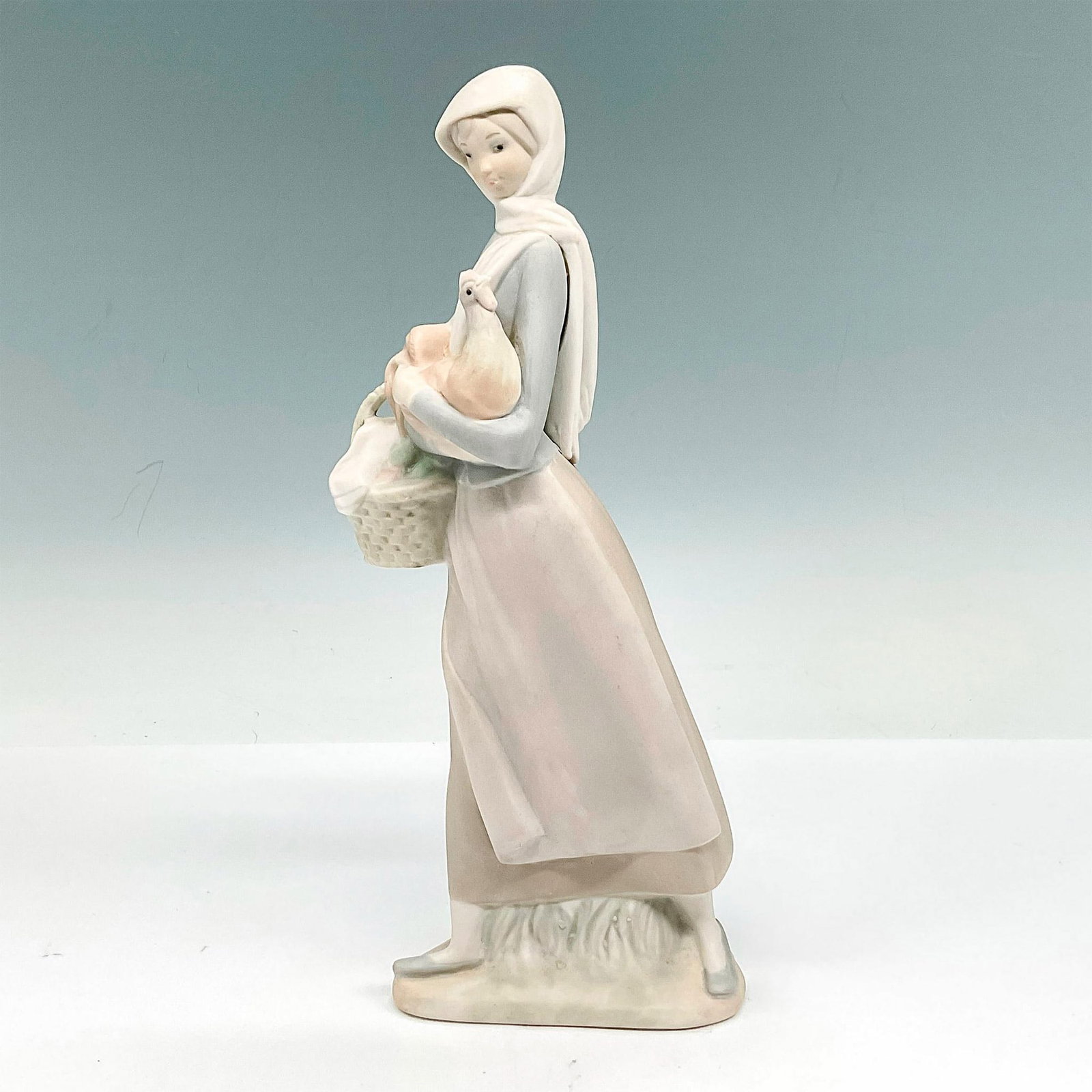 Girl with Cockerel 1014591 - Lladro Porcelain Figurine: Matte finished porcelain figurine of girl holding a cockerel and basket. Lladro backstamp. Artist: Fulgencio Garcia Issued: 20th Century Dimensions: 4.5"L x 3.25"W x 9.5"H Manufacturer: Lladro Countr
