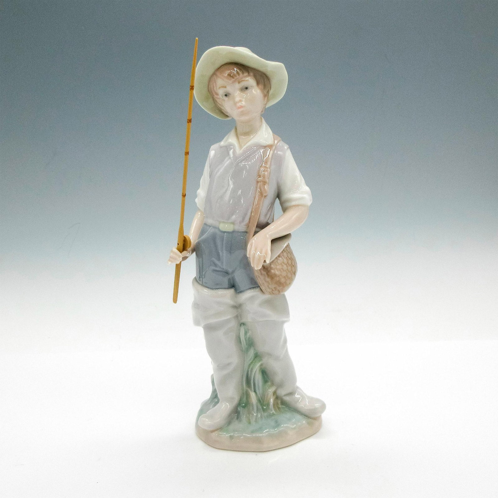 Going Fishing 1004809 - Lladro Porcelain Figurine: Glossy finish; Lladro backstamp. Artist: Salvador Furio Issued: 1972 - 2001 Dimensions: 8.5"H x 3.25"W Manufacturer: Lladro Country of Origin: Spain