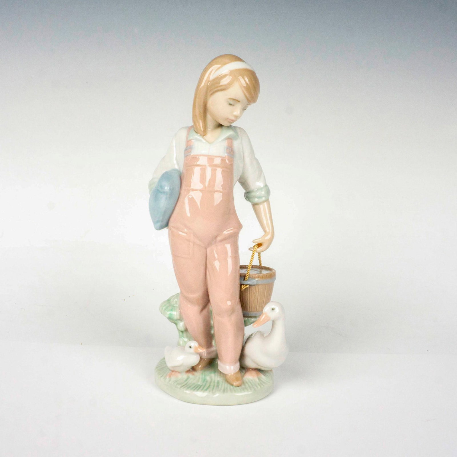 Saturday's Child (Girl) 1006022 - Lladro Porcelain Figurine: Glossy finish; Lladro backstamp. Includes original box. Box measures: 11.25"L x 5.5"W x 5"H. Artist: Juan Huerta Issued: 1993 - 1997 Dimensions: 7.5"H Manufacturer: Lladro Country of Origin: Spain